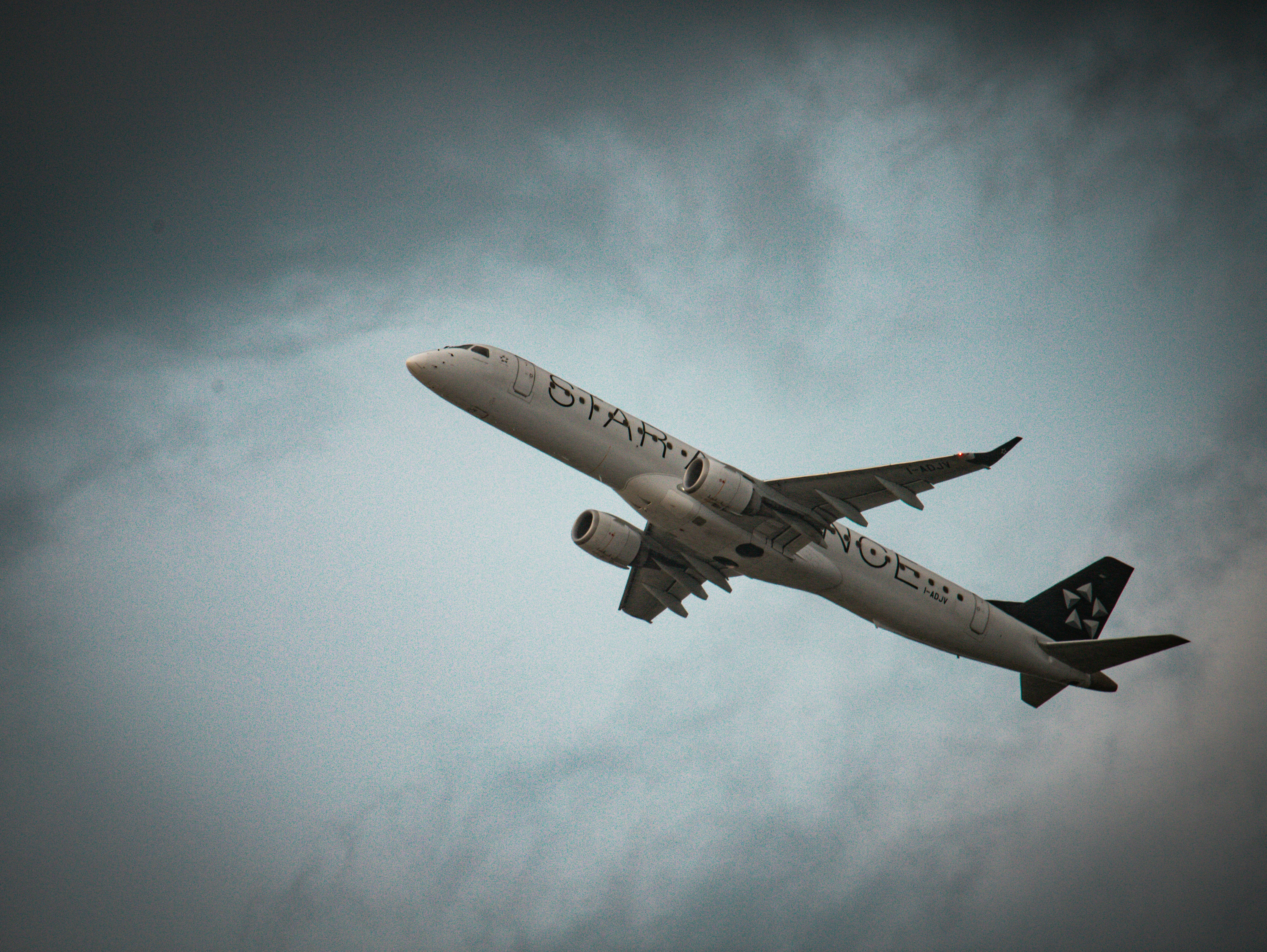 A commercial airplane ascends into a cloudy sky.
