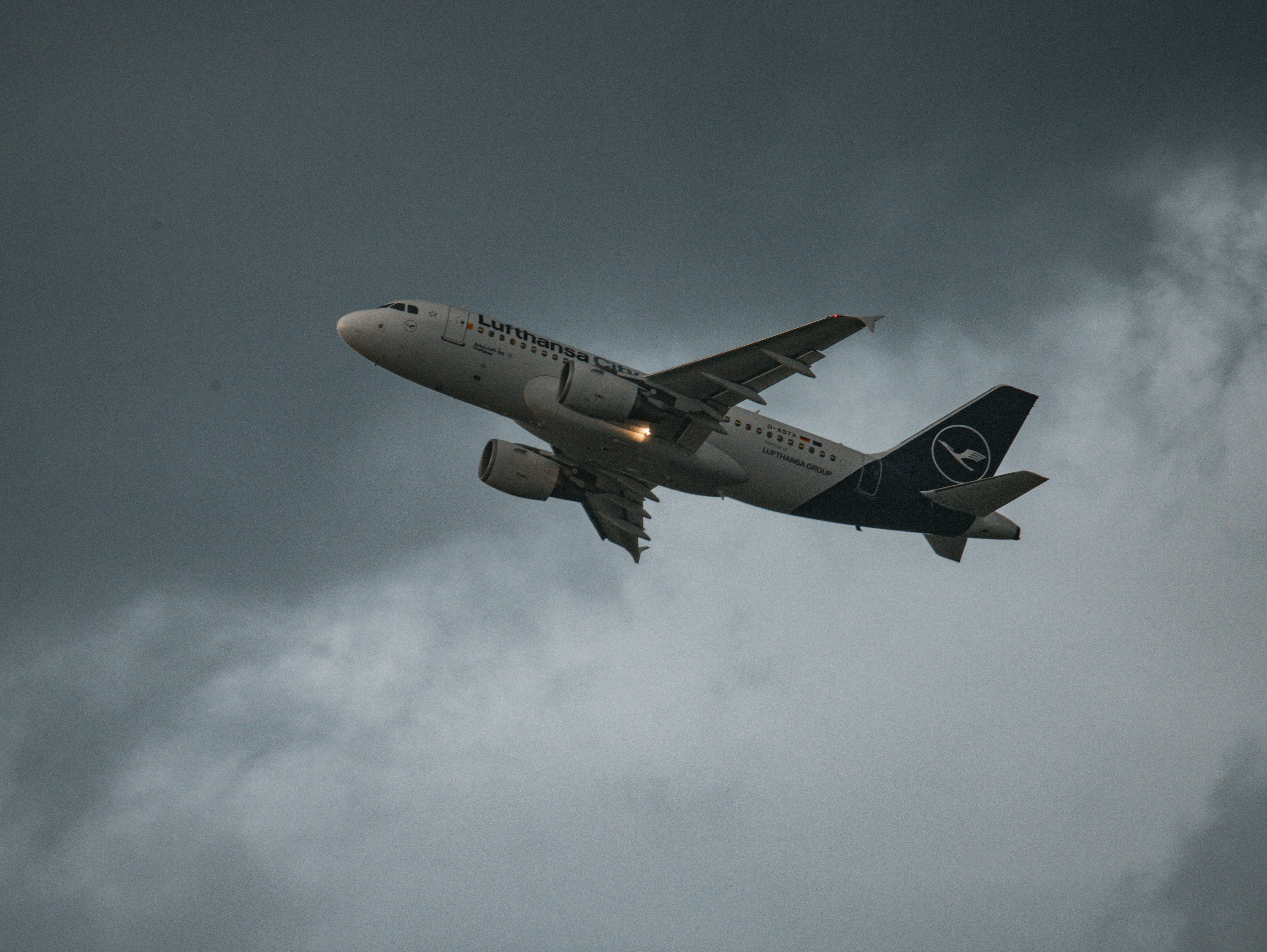 A lufthansa airplane ascending into a cloudy sky.