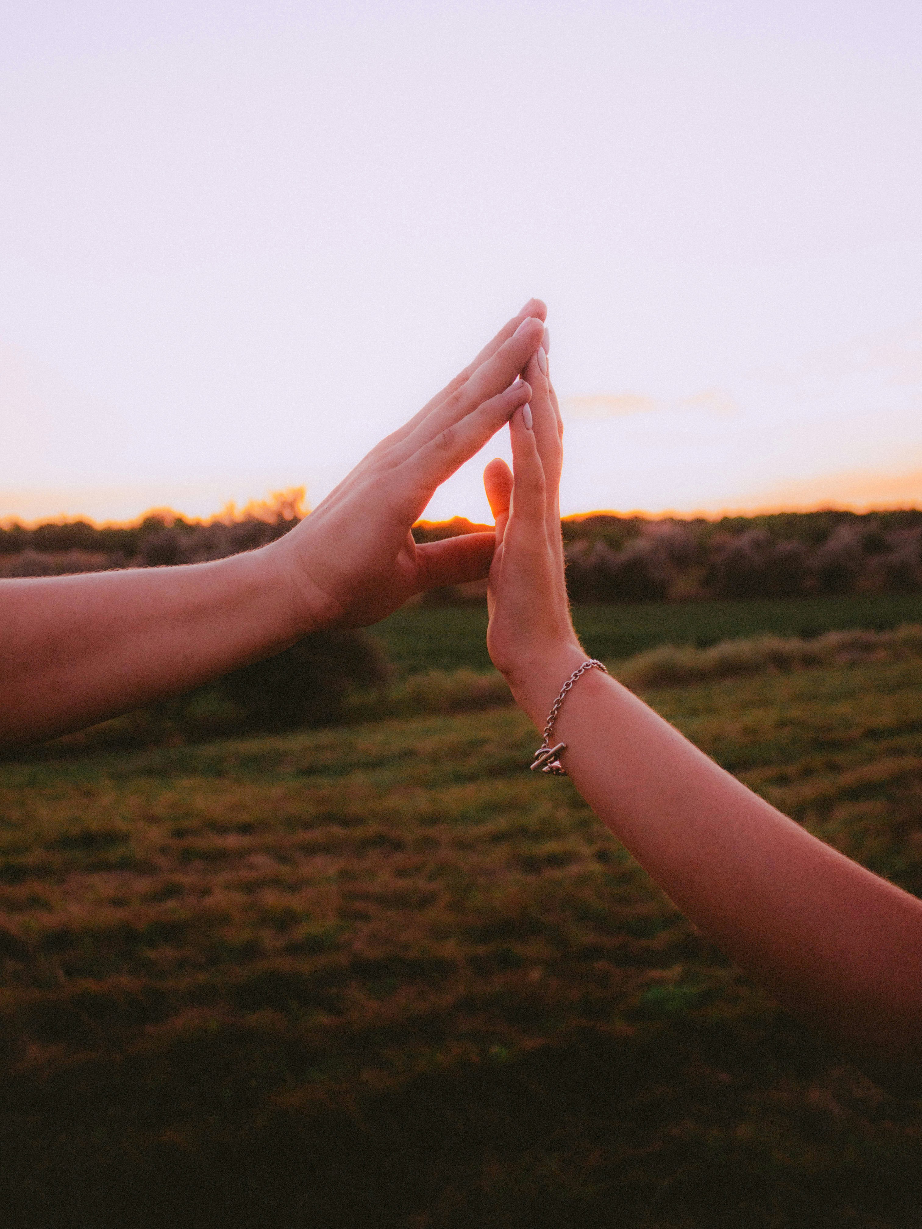 Deux mains qui donnent un high five au coucher du soleil