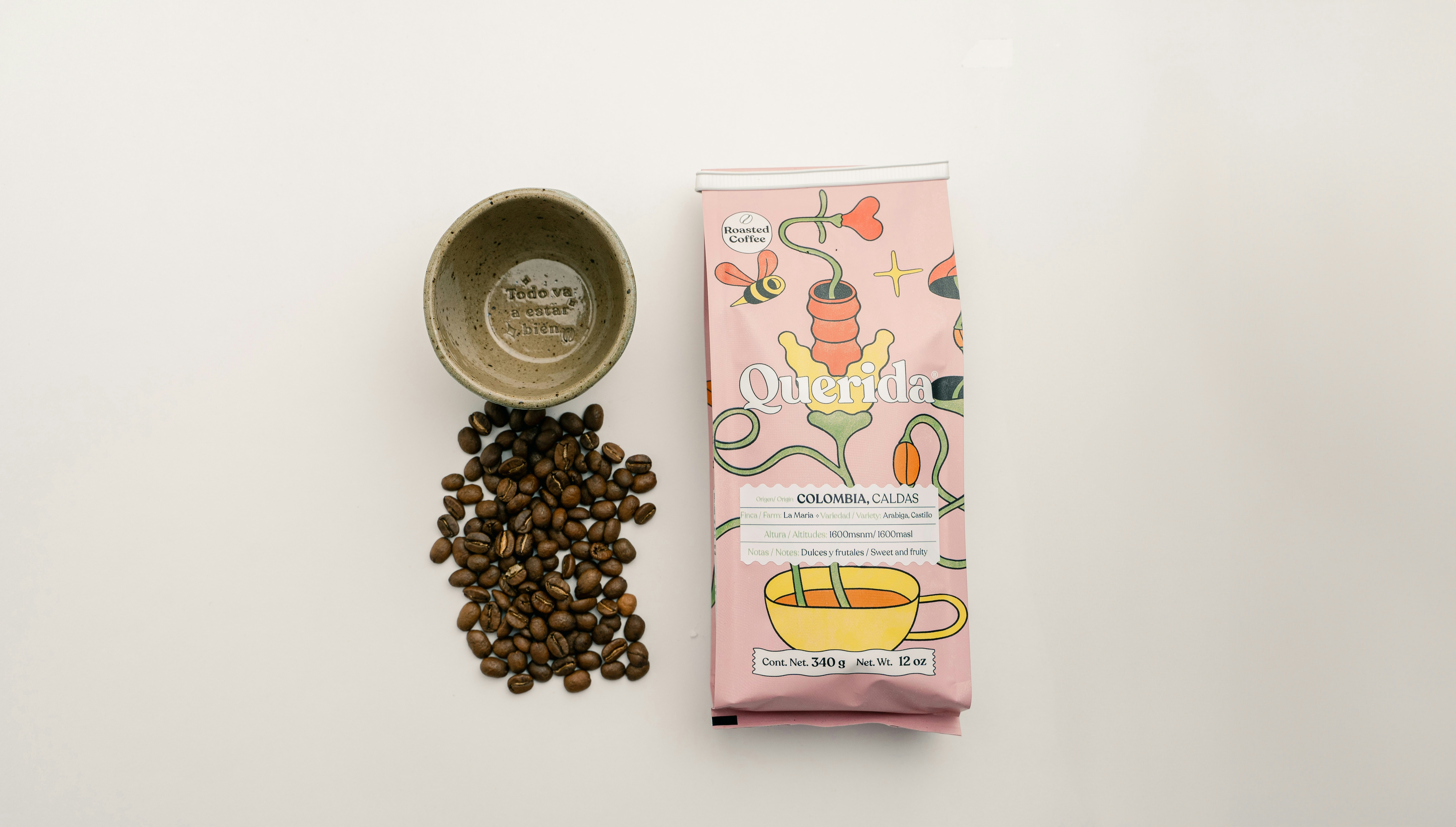 Coffee beans next to a pink coffee bag