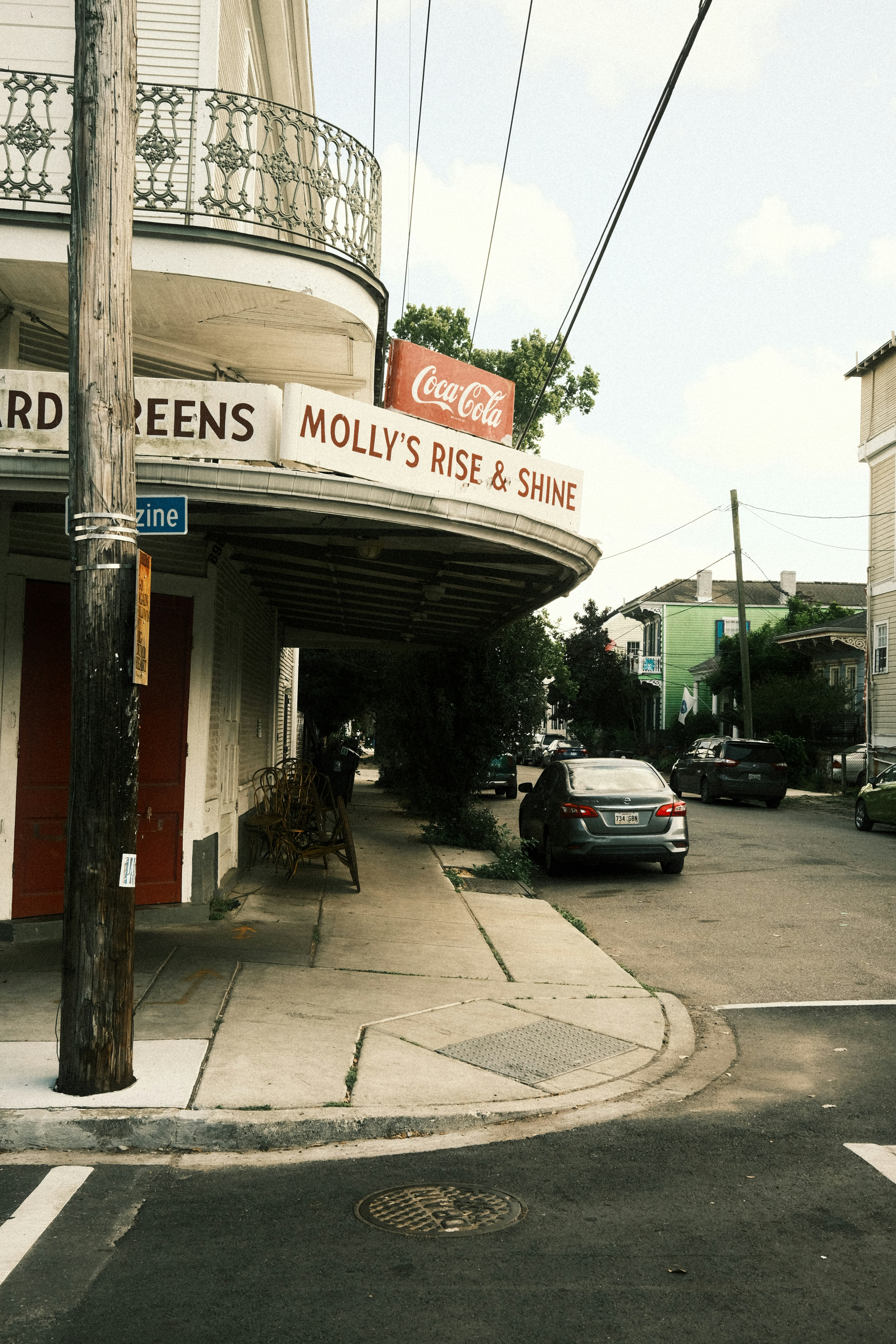 Tienda de la esquina con cartel de Coca-Cola y coches en la calle.