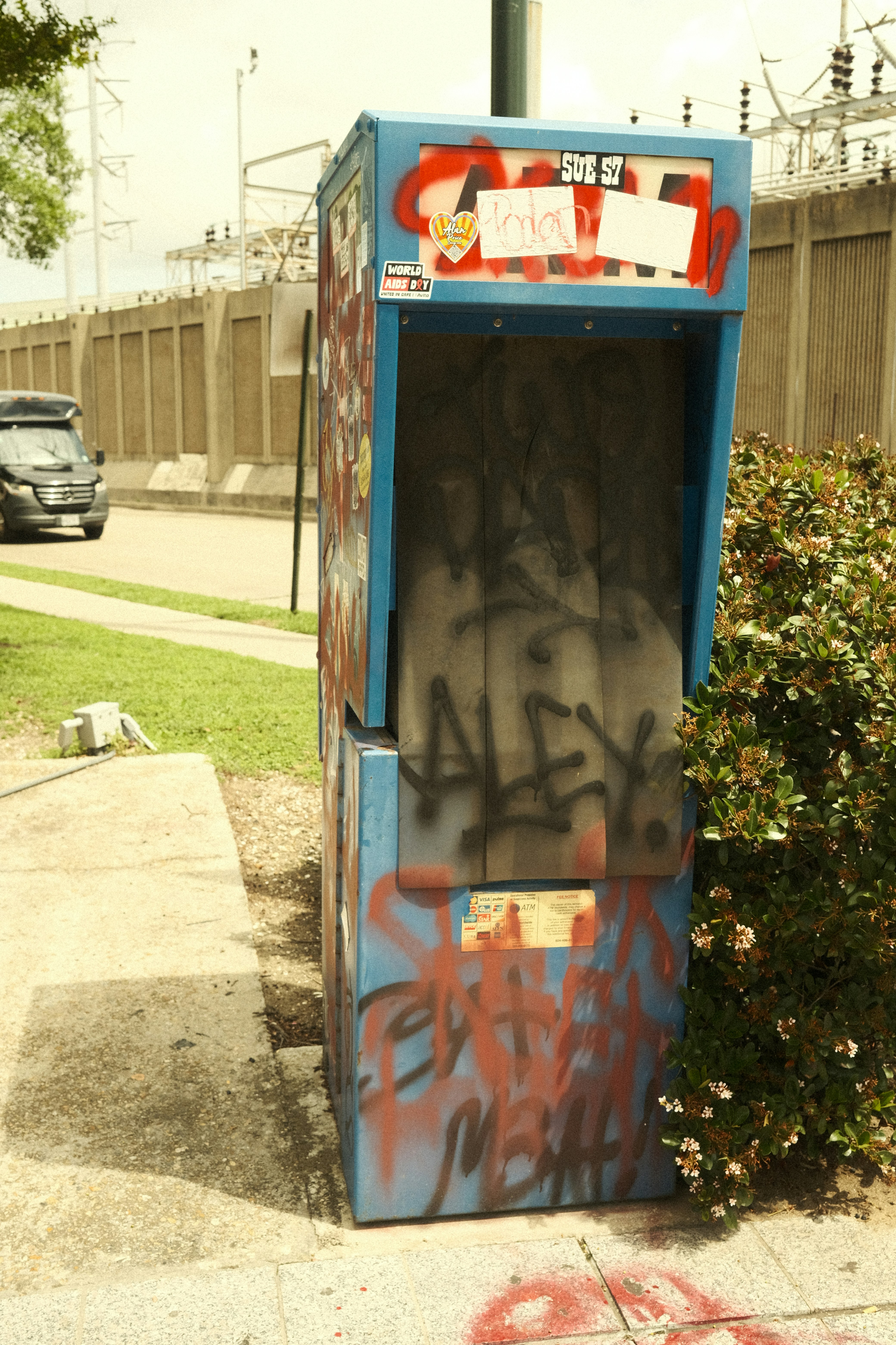 Cabina de teléfono público azul cubierta de grafitis en la acera