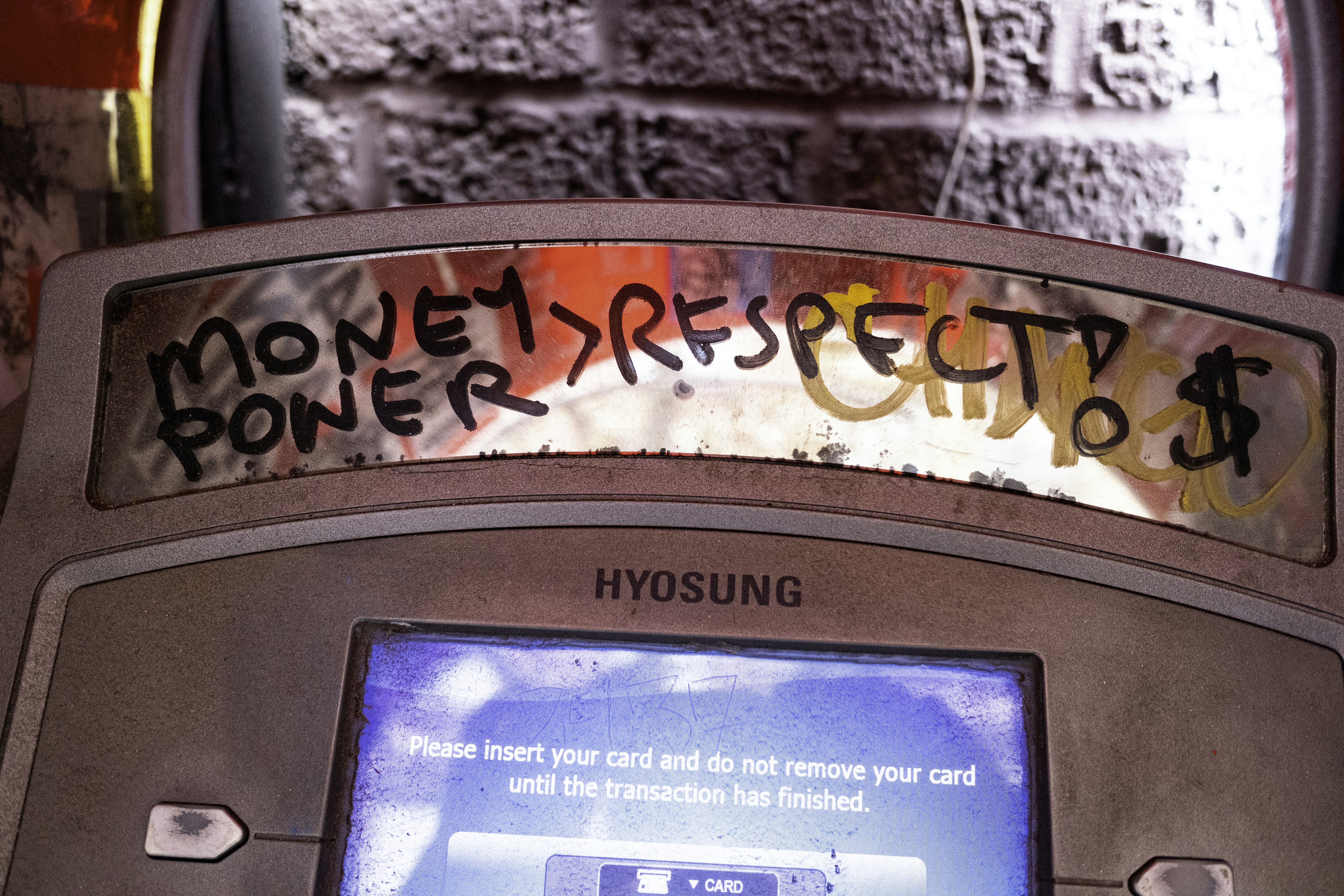 Graffiti on atm reads money, power, respect, and dollar sign.
