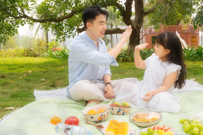 Father and daughter giving high fives at a picnic.
