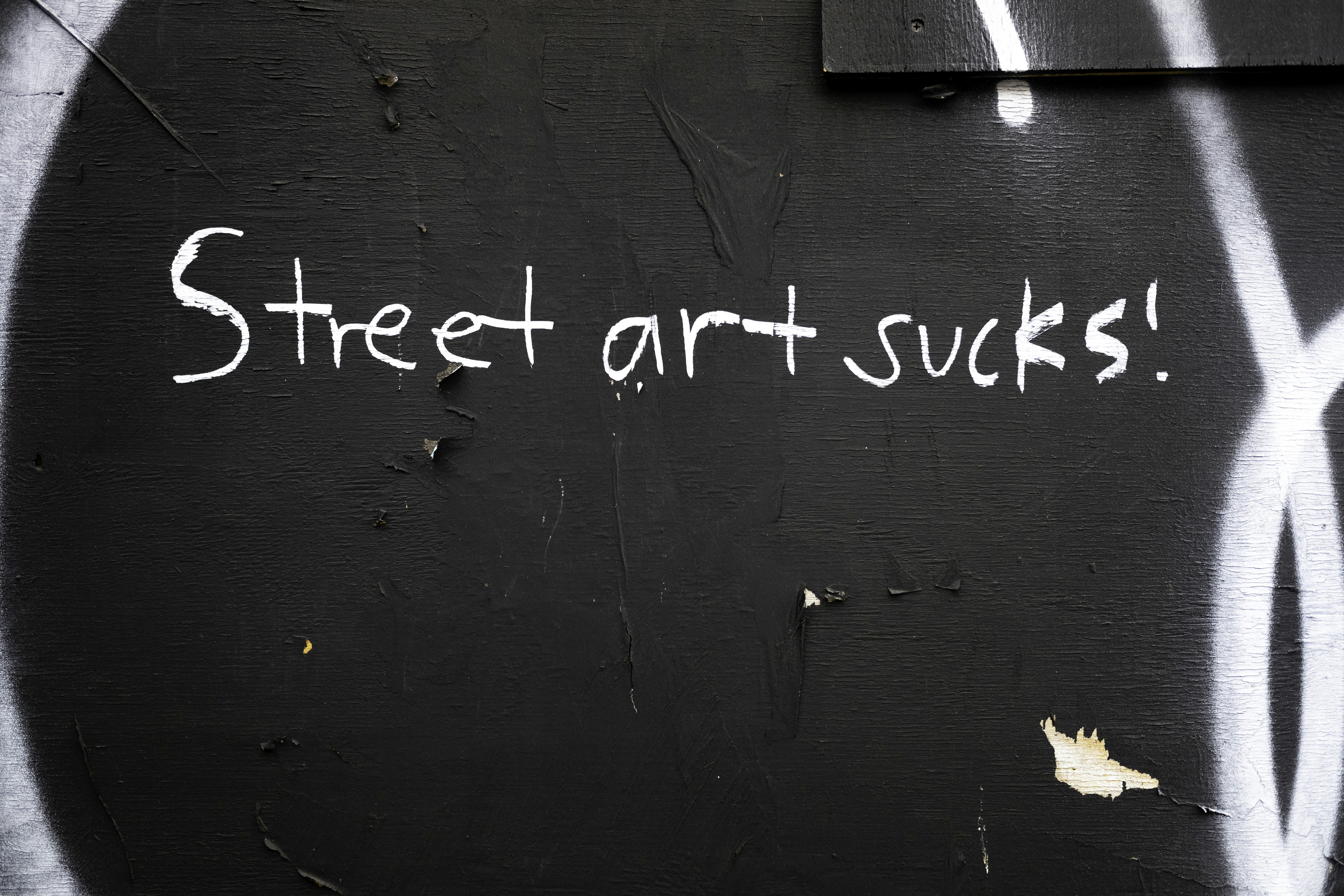 Street art sucks text written on a dark wall