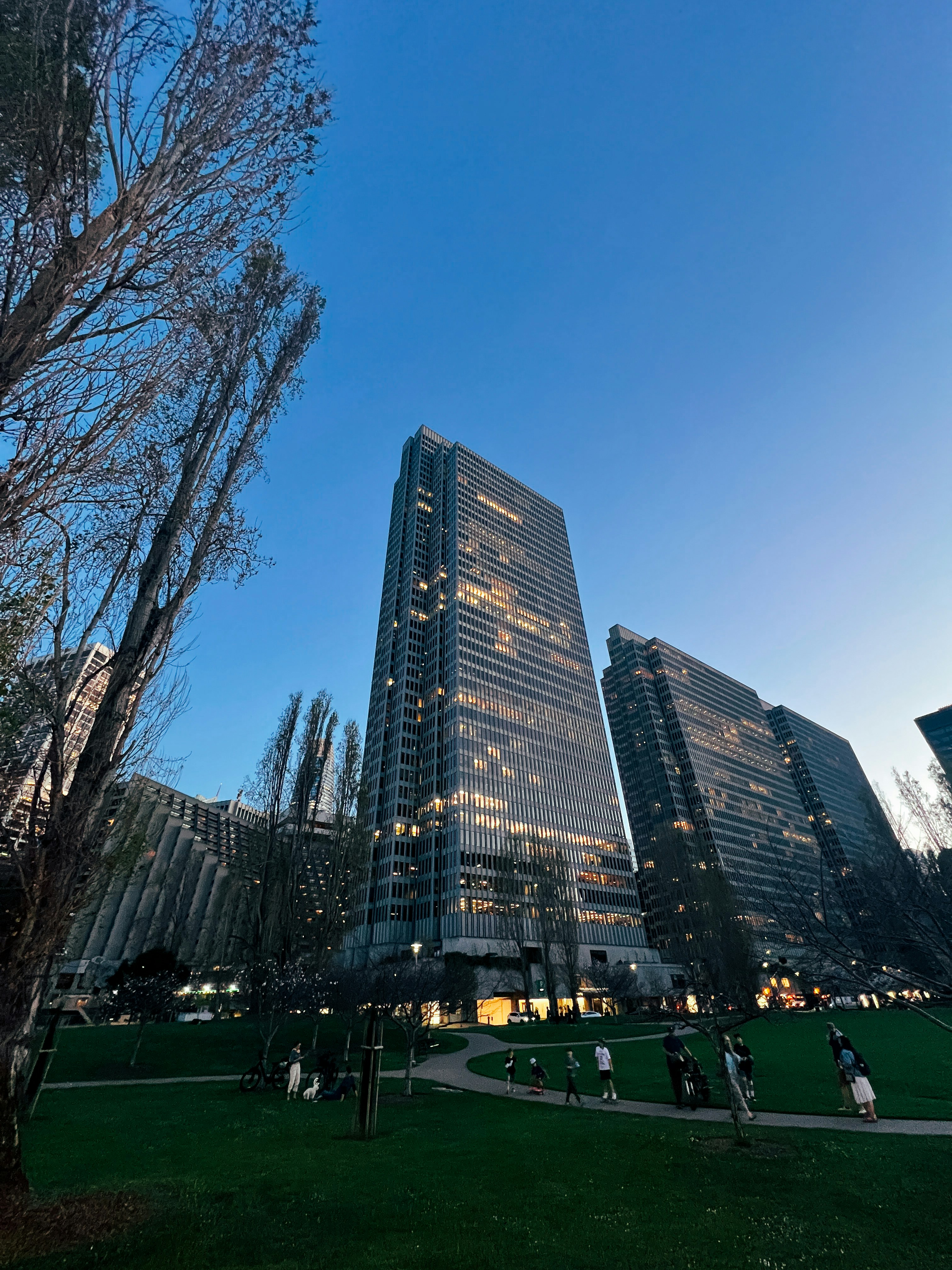 Tall glass skyscrapers illuminated against a clear blue sky.