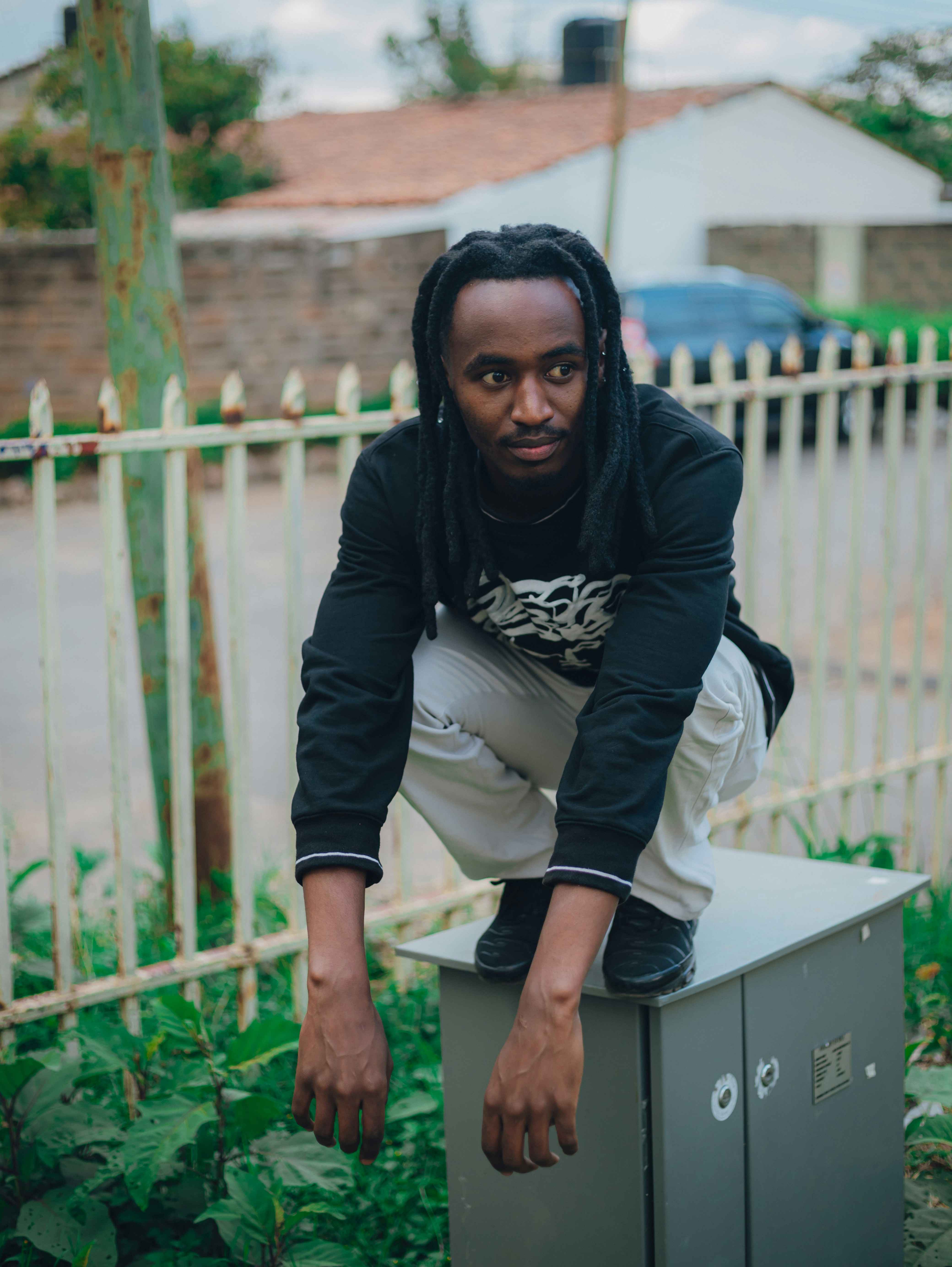 Ein Mann mit Dreadlocks hockt auf eine Baukaste.