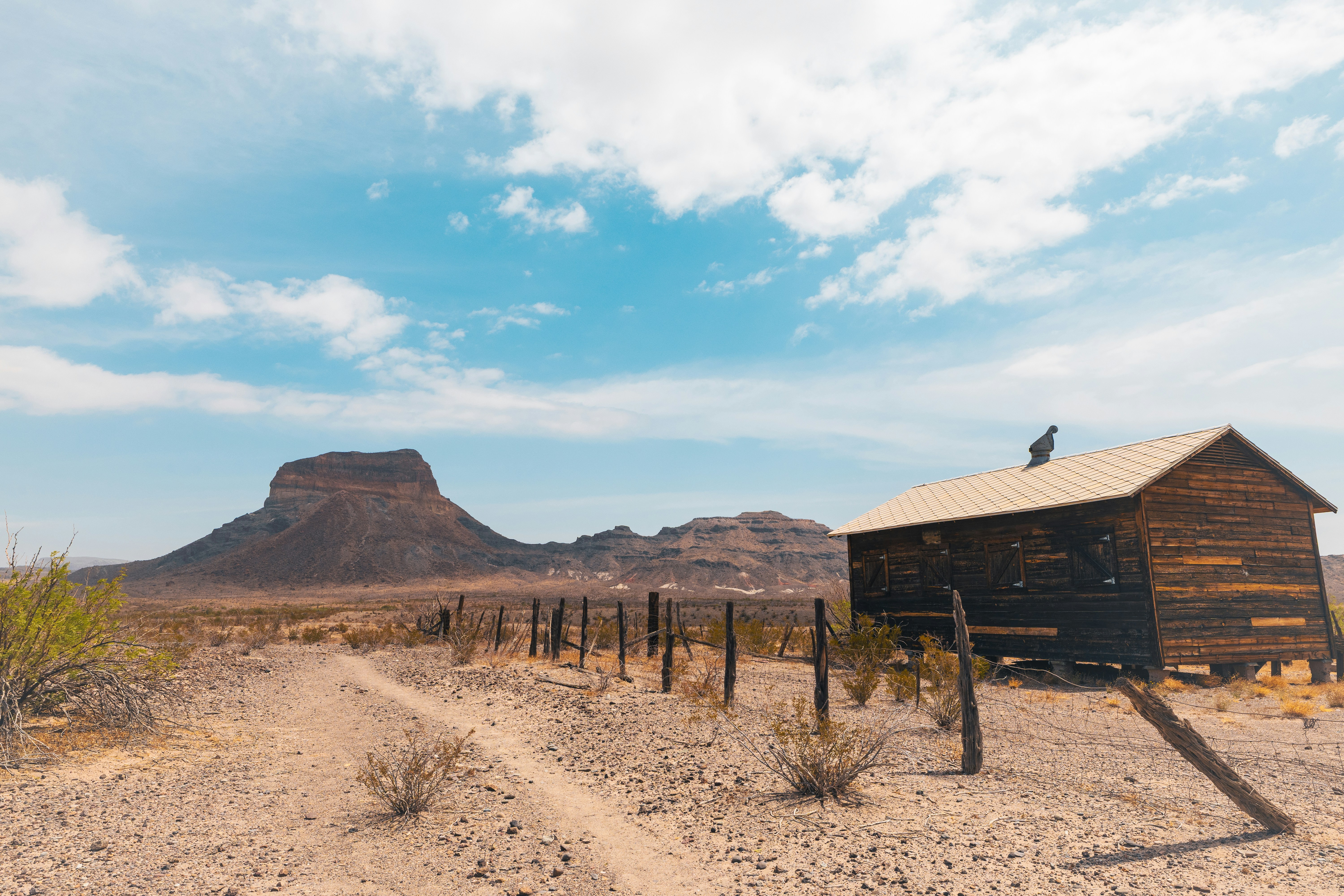 Rustic wooden cabin in a desert landscape with mountains.