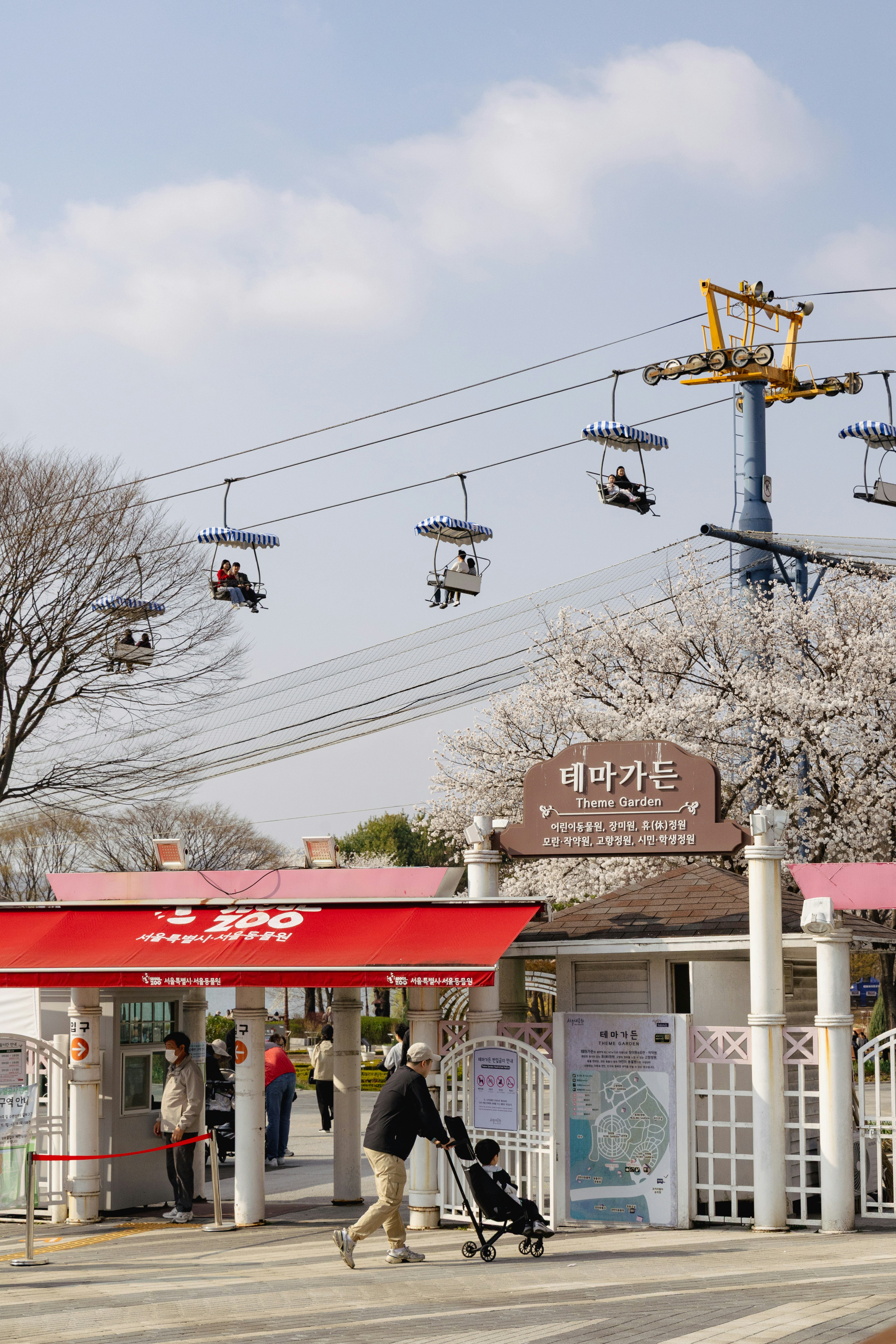 People ride a sky lift over an amusement park entrance.
