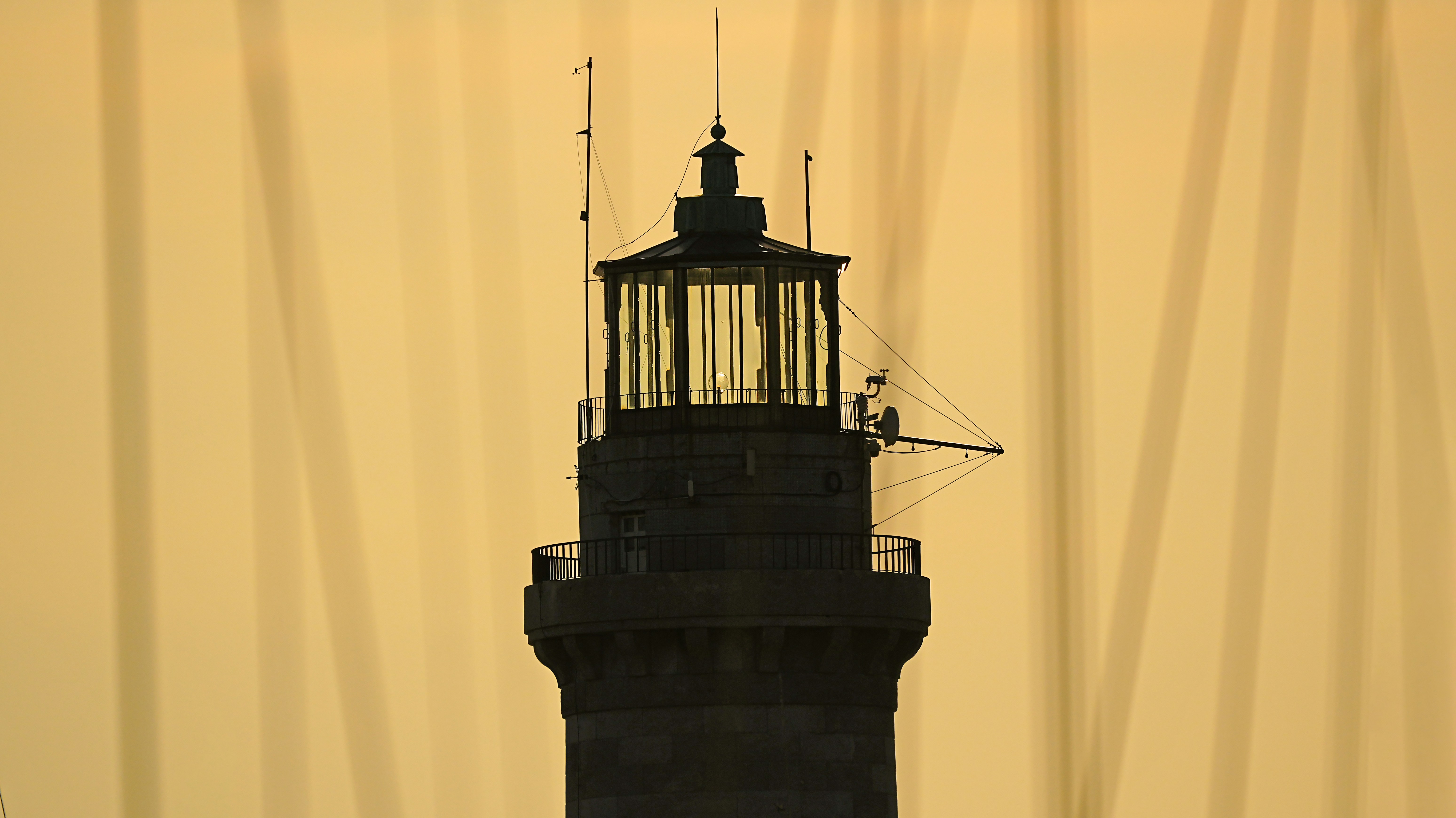 Silhouette d’un phare sur un ciel doré