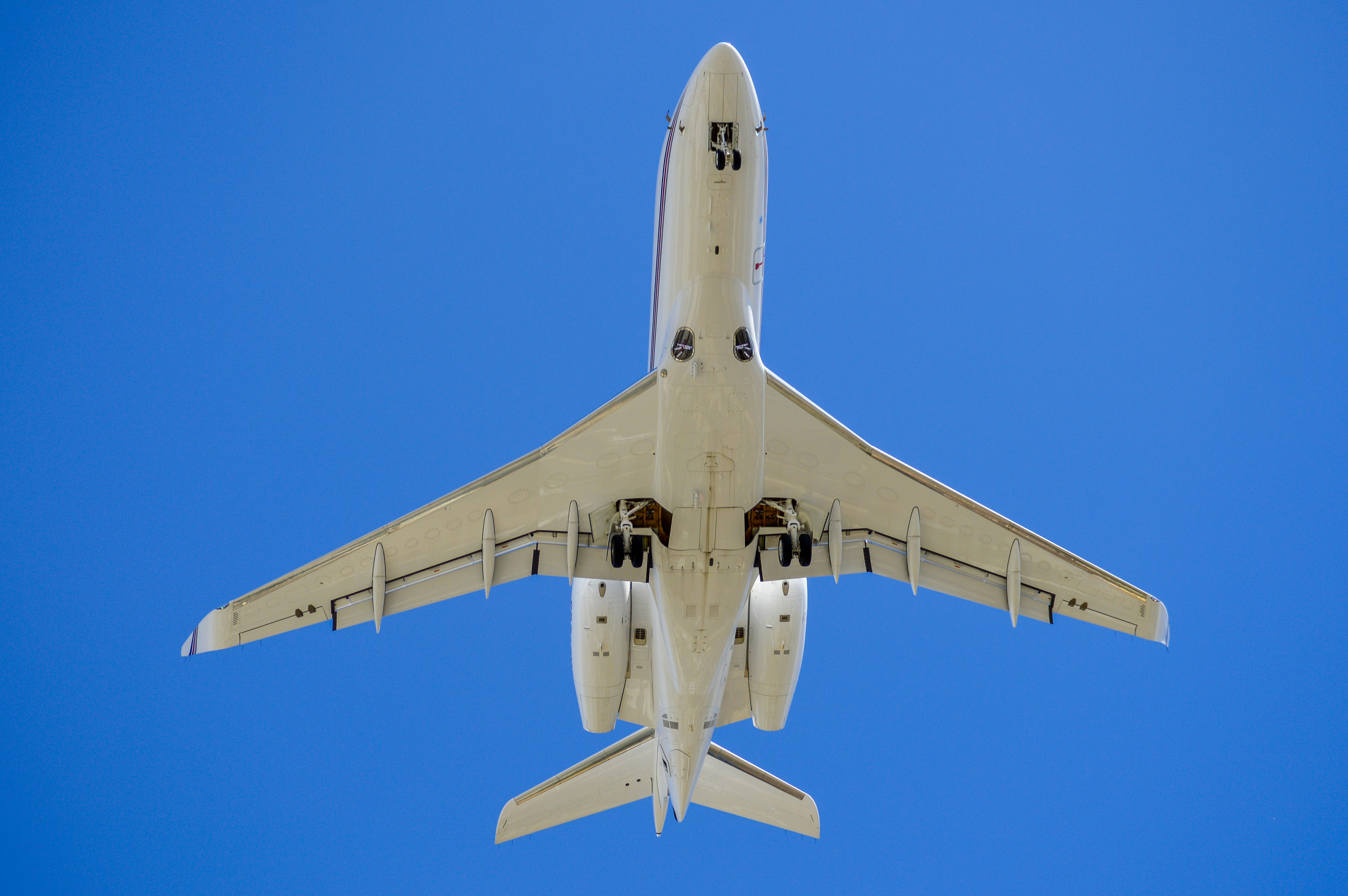 A white airplane flying in a clear blue sky