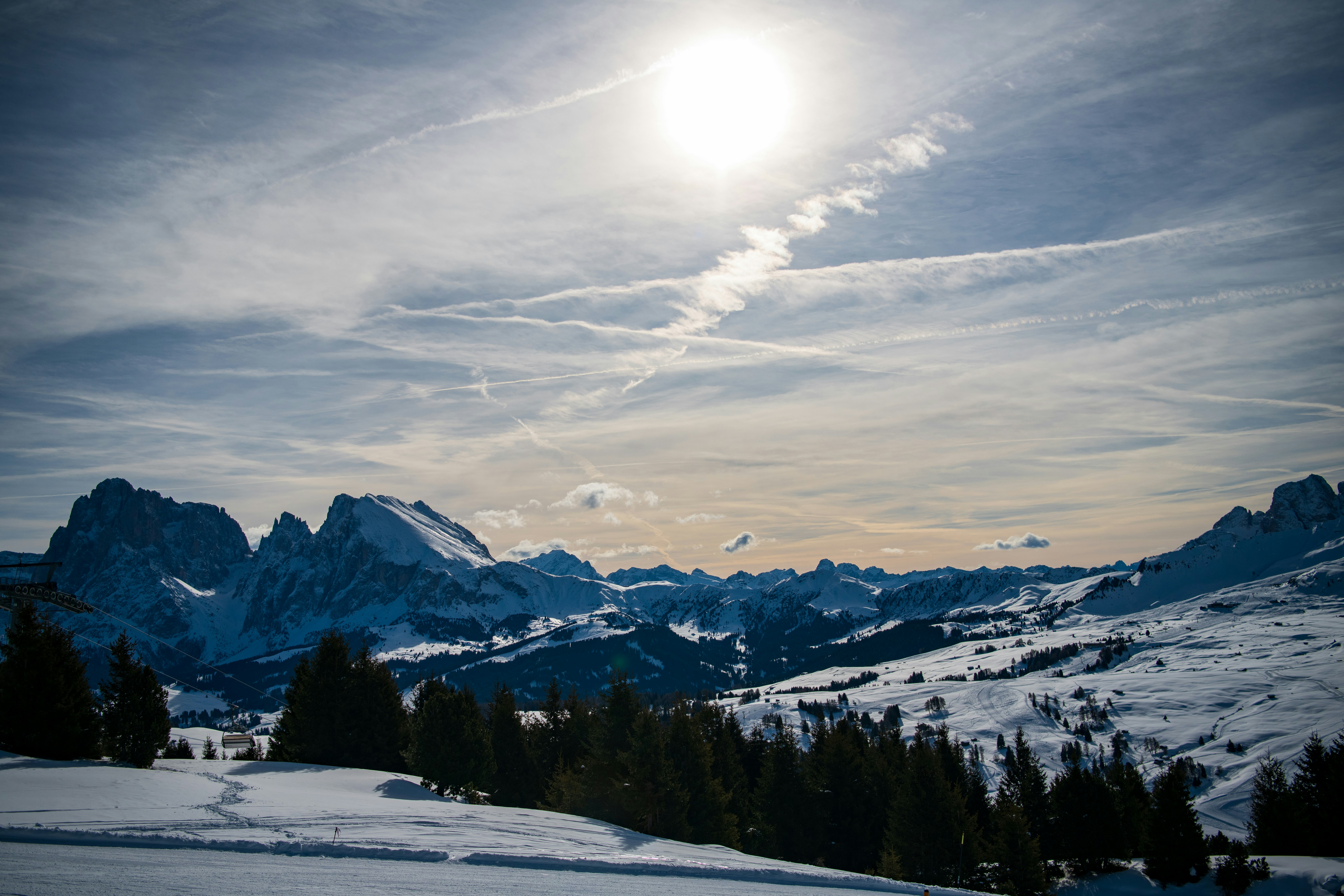Snowy mountain range under a bright, cloudy sky