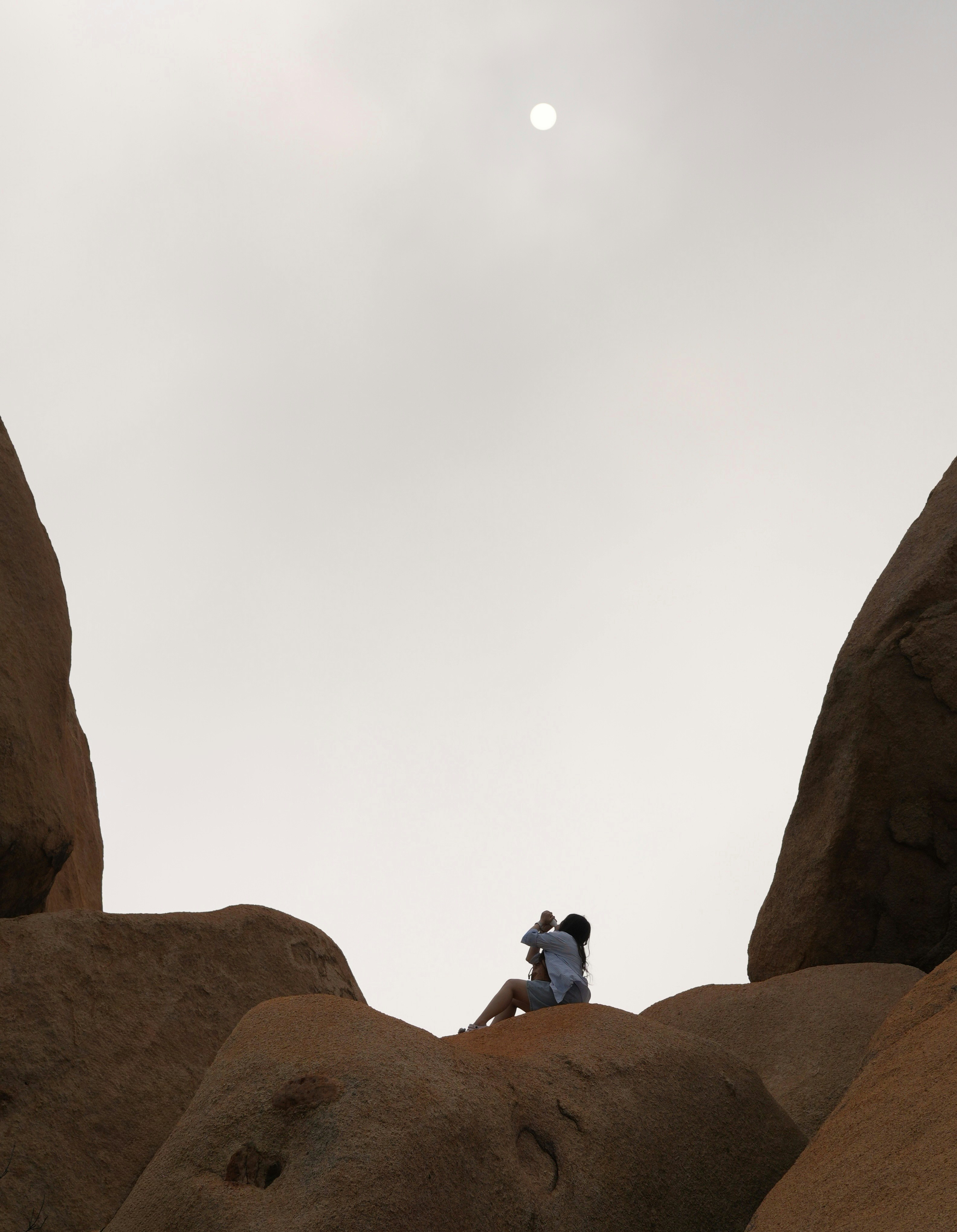 Paar, das sich auf Felsen umarmt, mit Sonne über dem Kopf