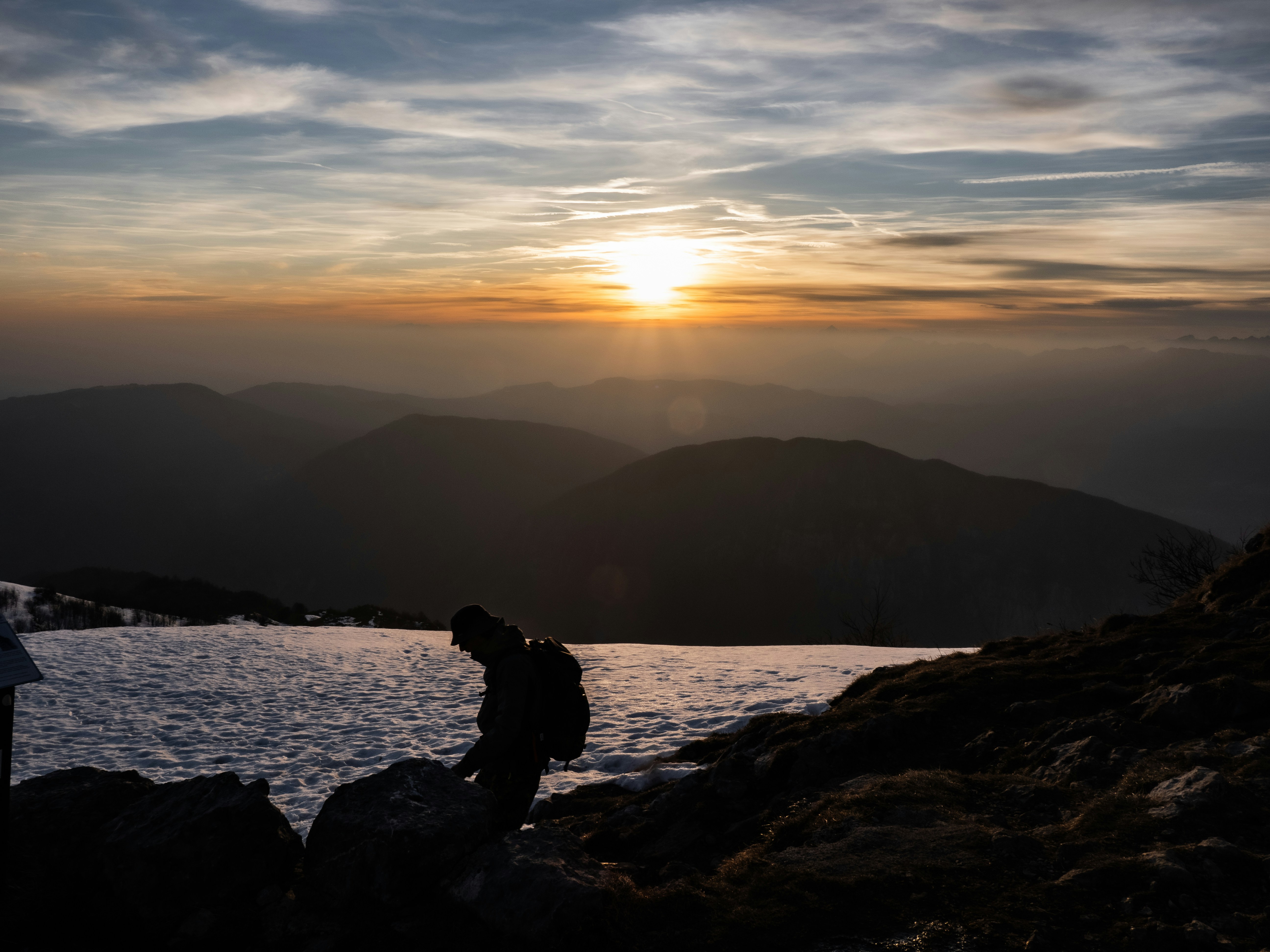 Silhouette eines Wanderers bei Sonnenuntergang auf einem Berg.