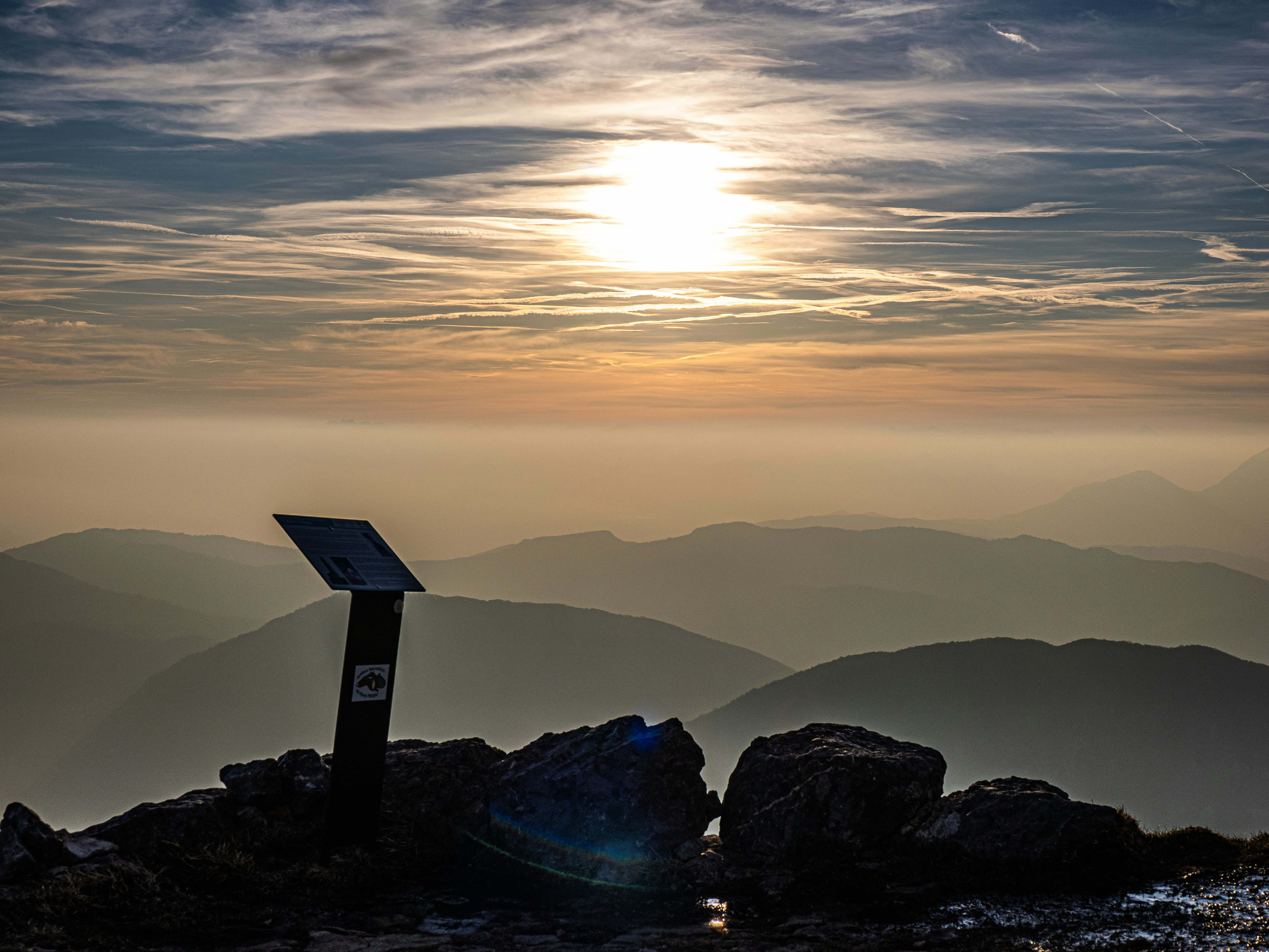 Sonnenaufgang über nebligen Berggipfeln mit einer Markierung.