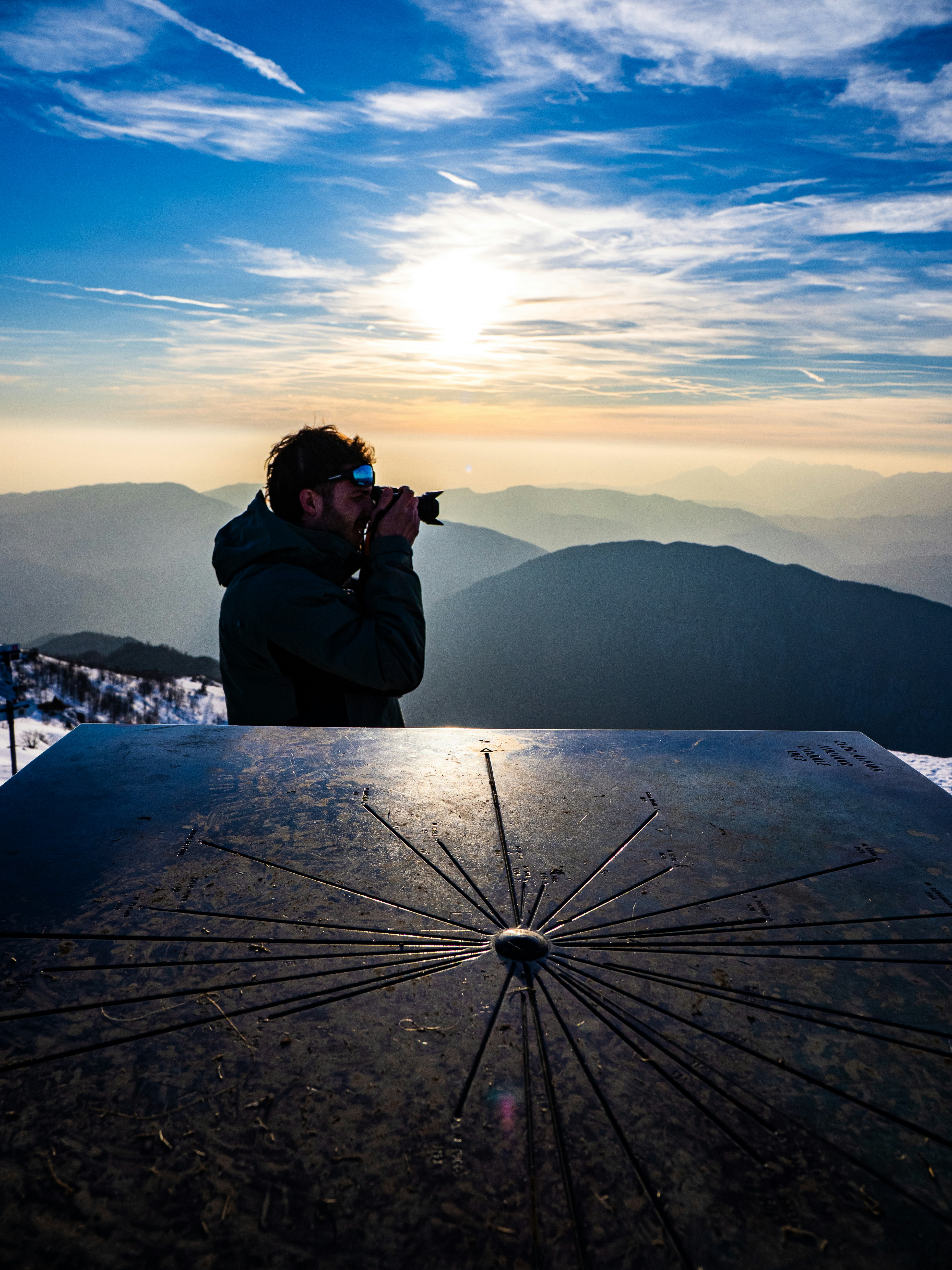 Mann, der bei Sonnenaufgang auf einem Berggipfel Kaffee trinkt