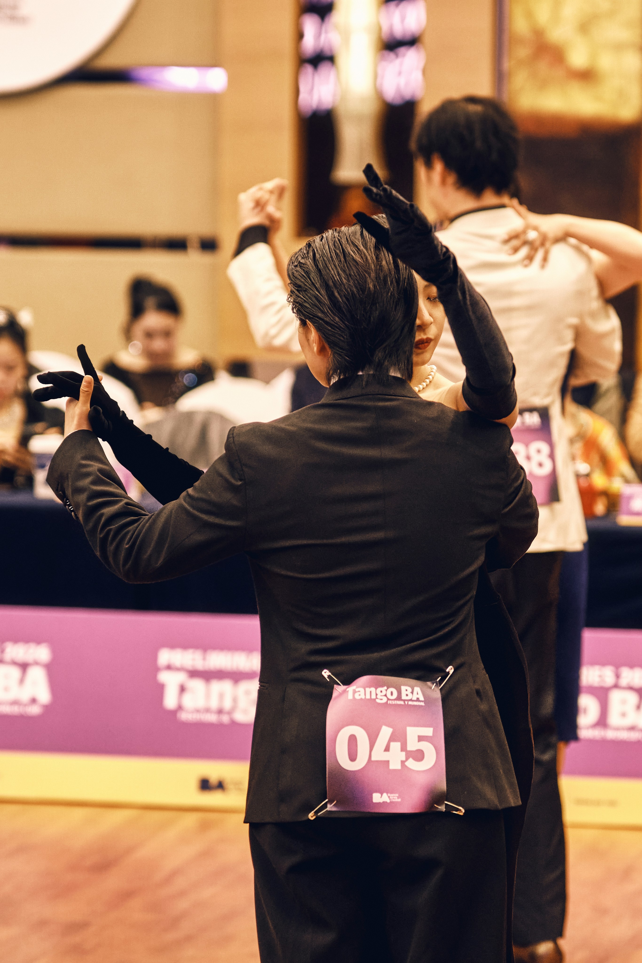 Des danseurs en tenue formelle s’affrontent lors d’un événement de salon.