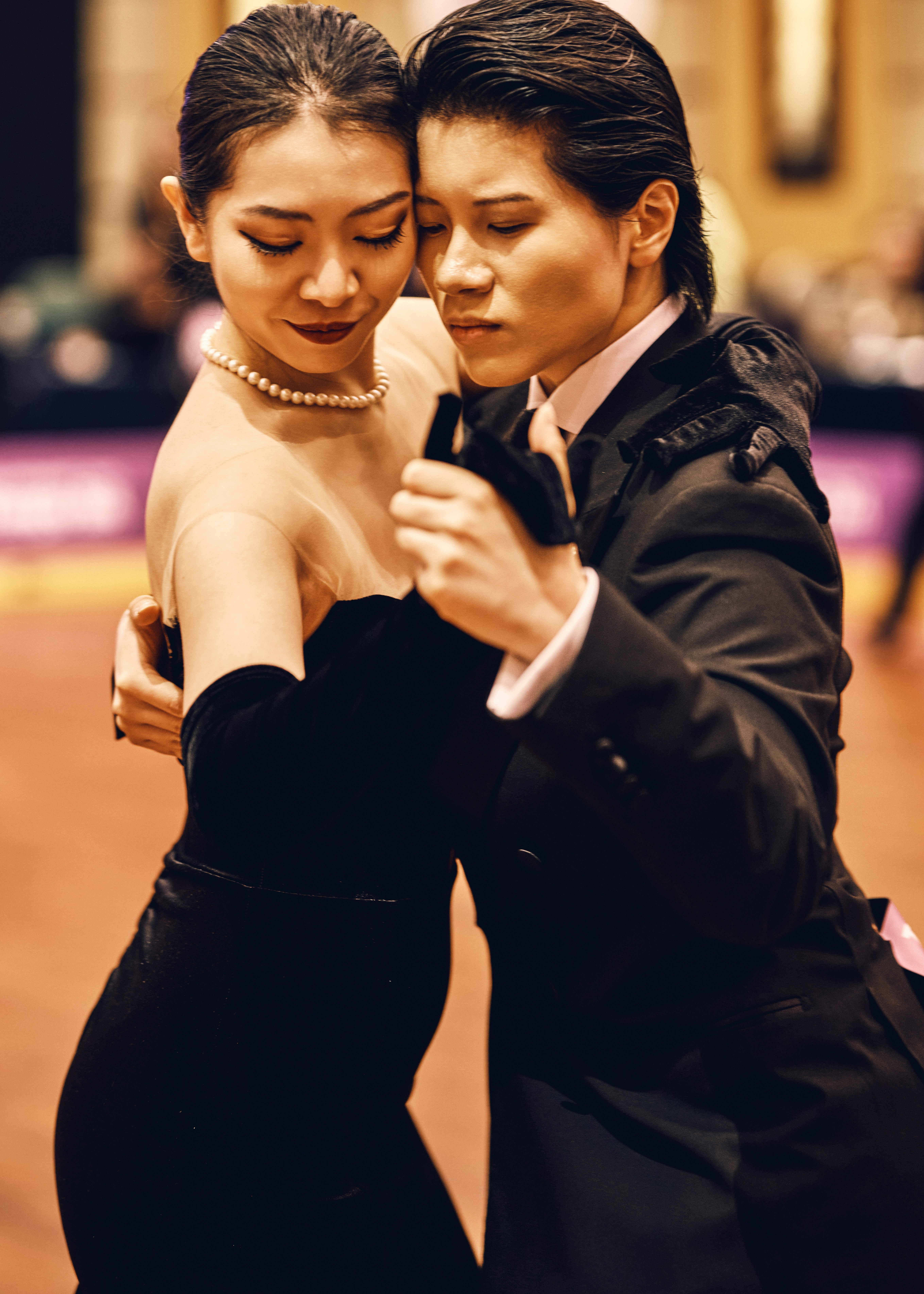 Un couple dansant dans une salle de bal en tenue formelle.