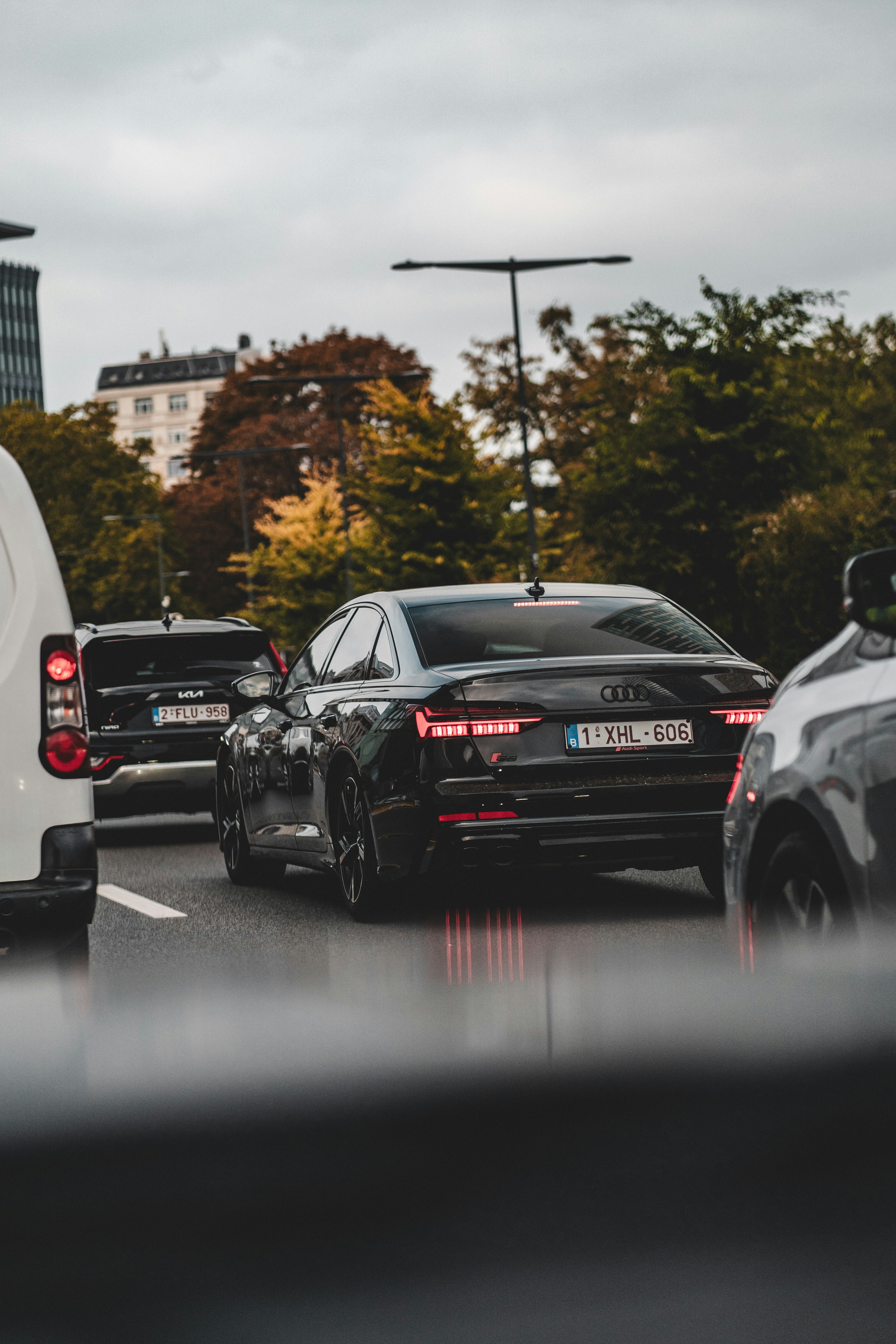 Black audi sedan driving on a wet city street.