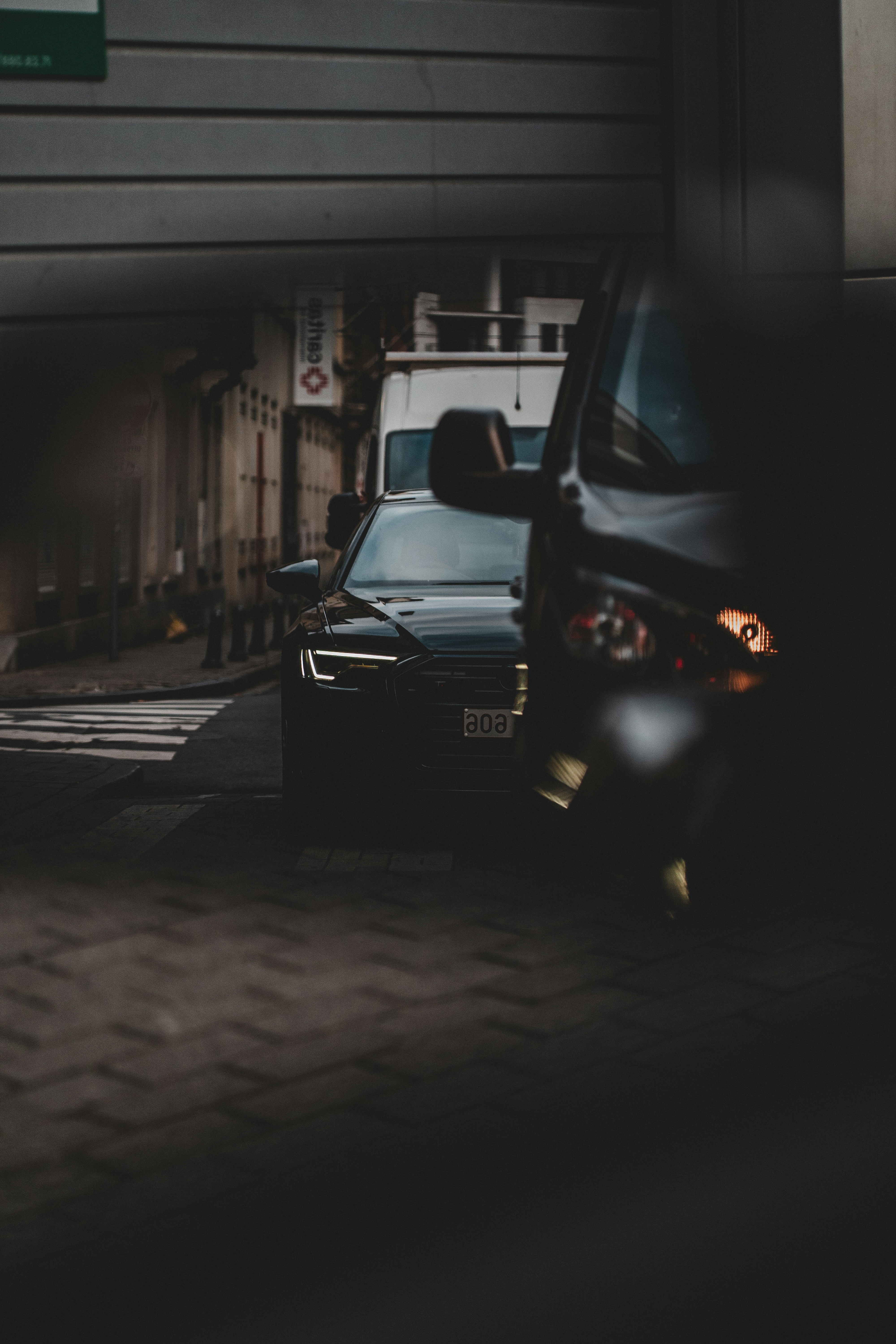 Two cars parked under a bridge at dusk