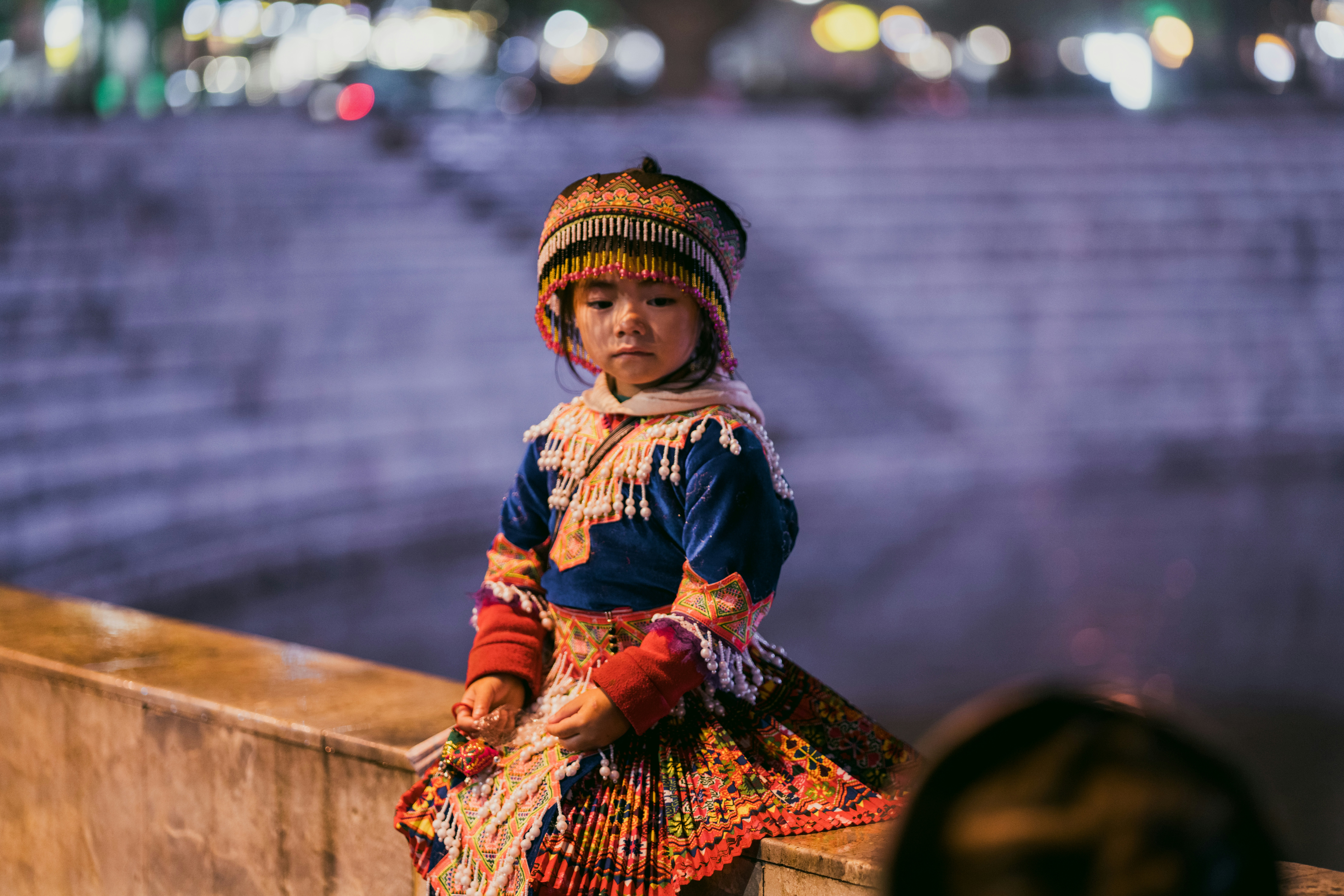 Young girl in traditional clothing sits outdoors at night