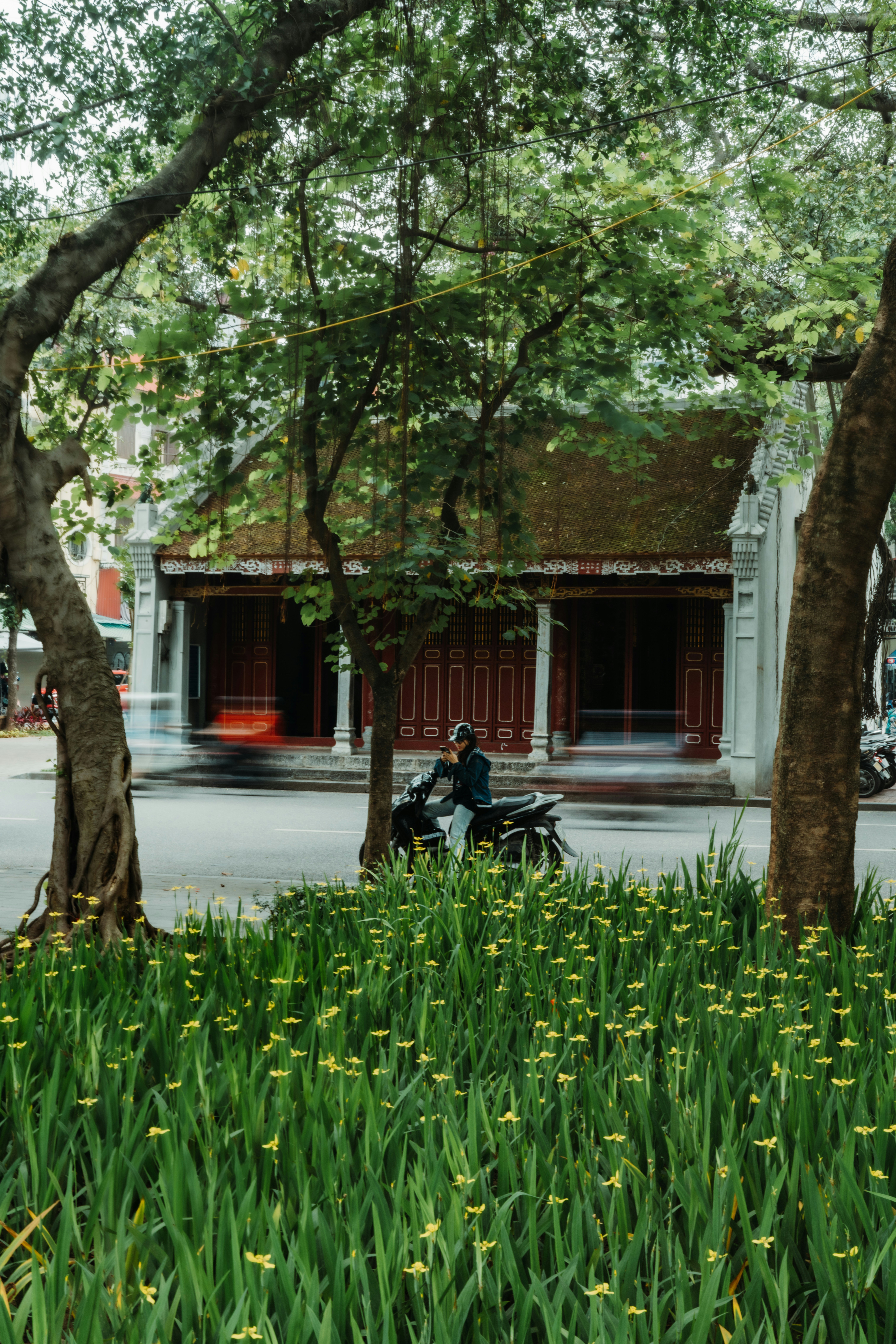 Motorcyclist rides past a traditional building