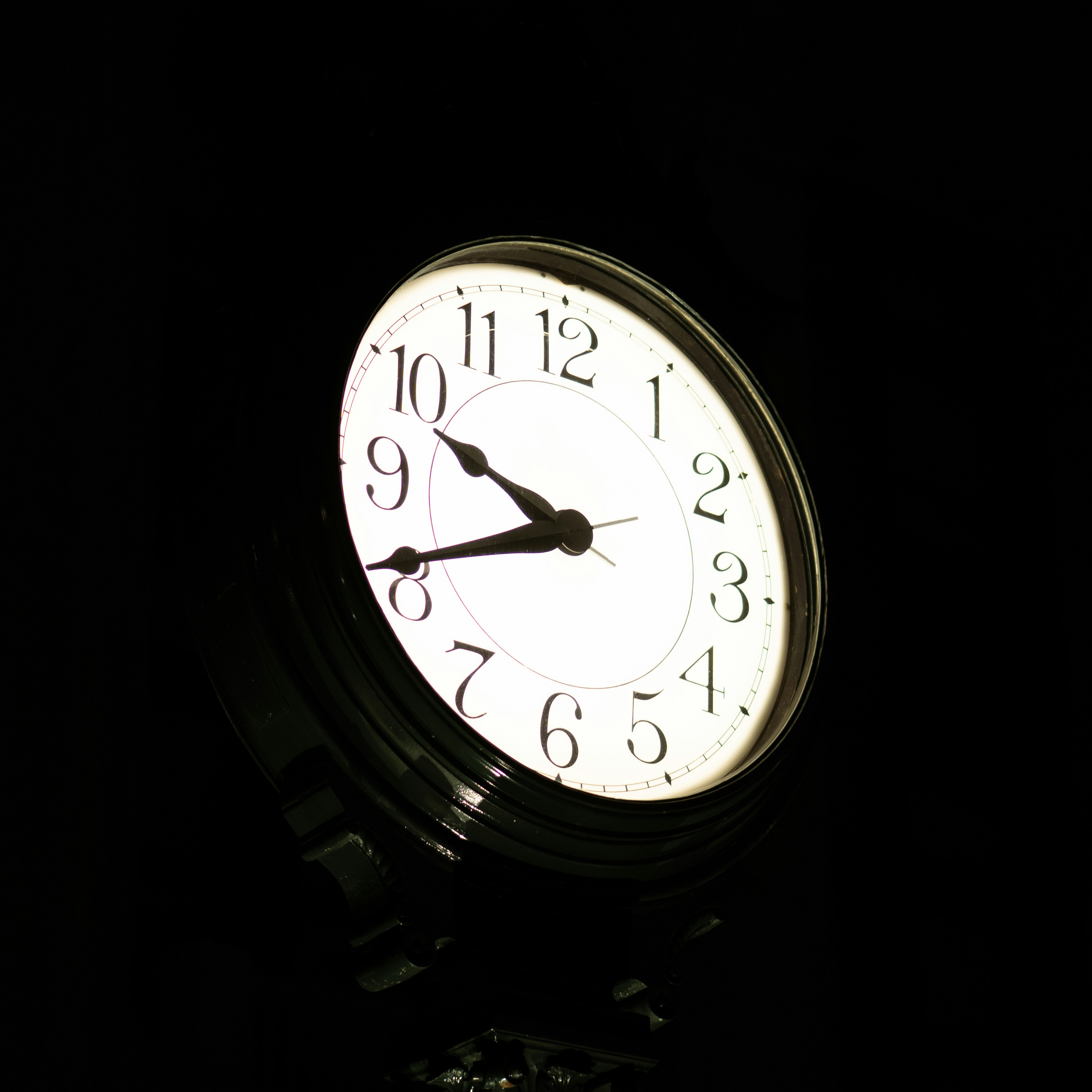 A close-up of a white clock face at night.