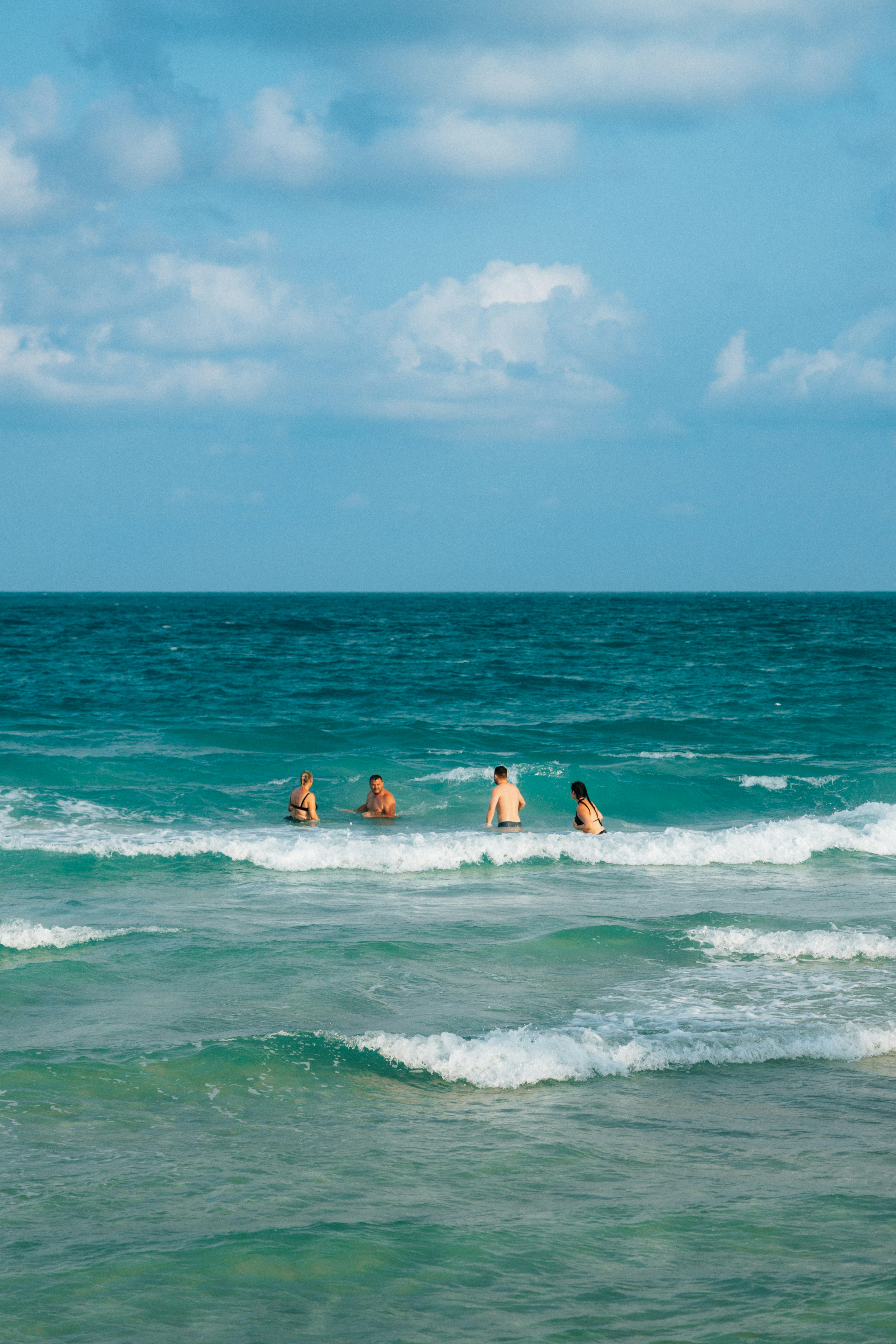 Four people swim in the ocean waves