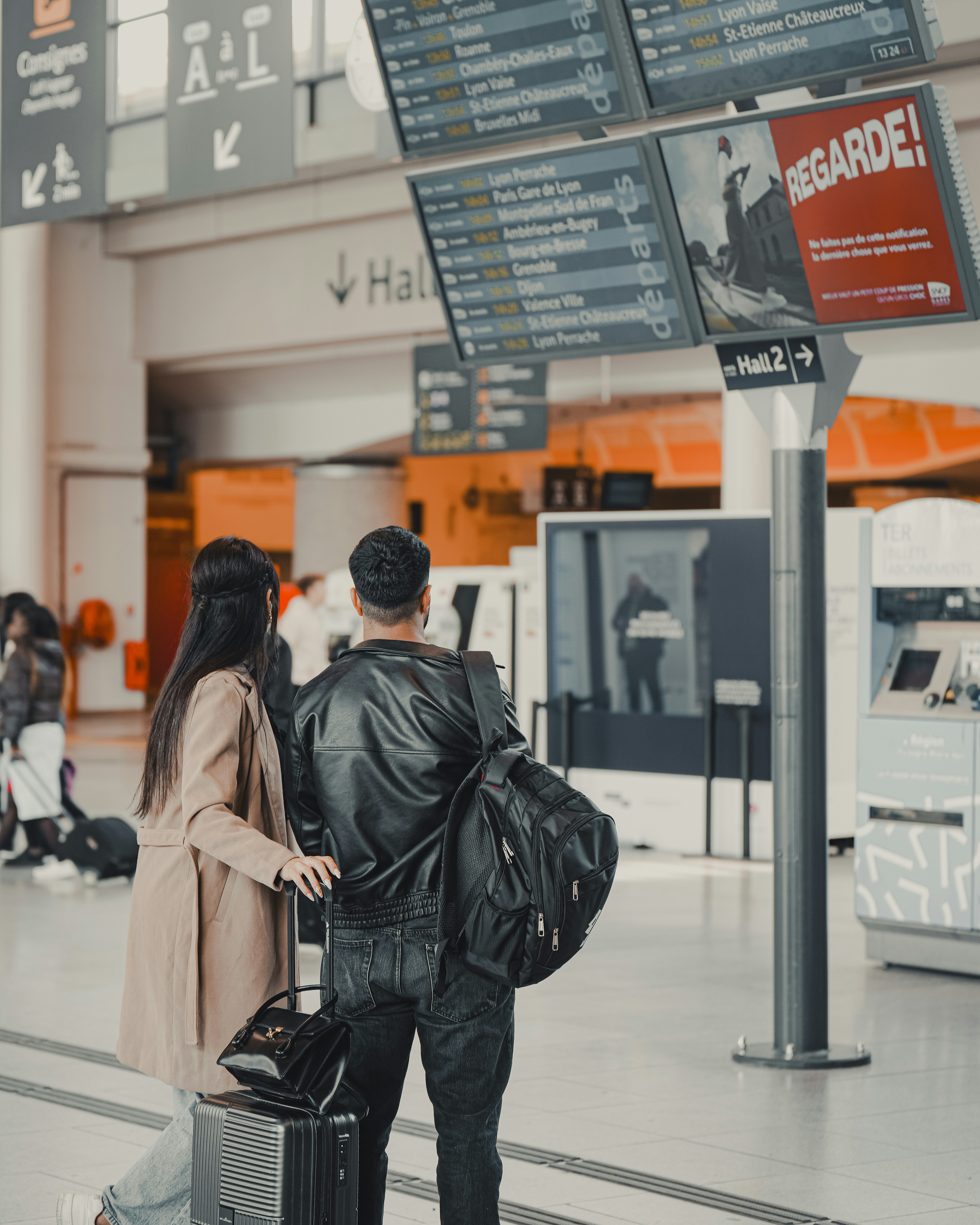 Ein paar schaut sich Abflugtafeln im Flughafenterminal an.