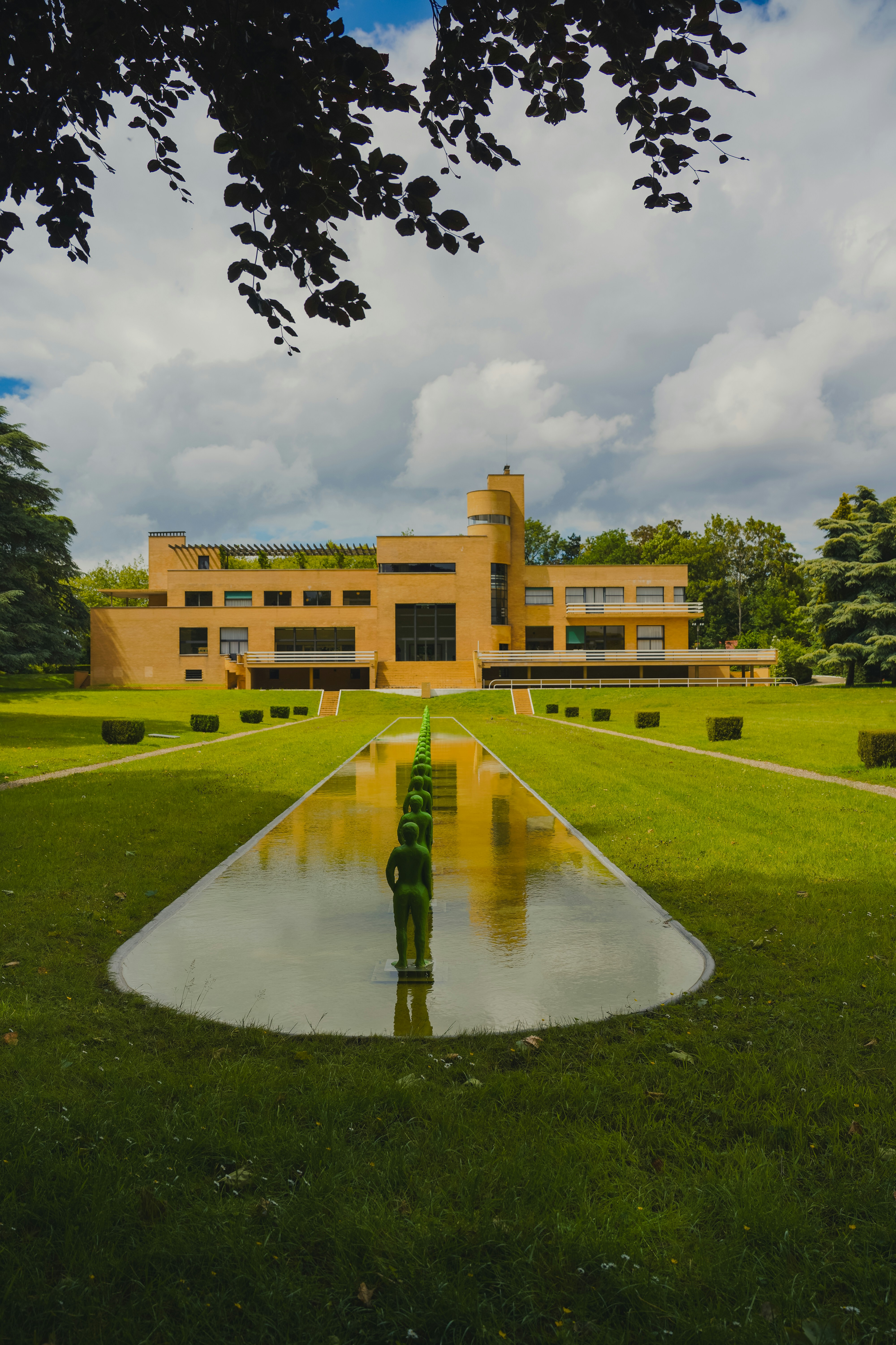 Modernes gelbes Gebäude mit Spiegelbecken und Rasen