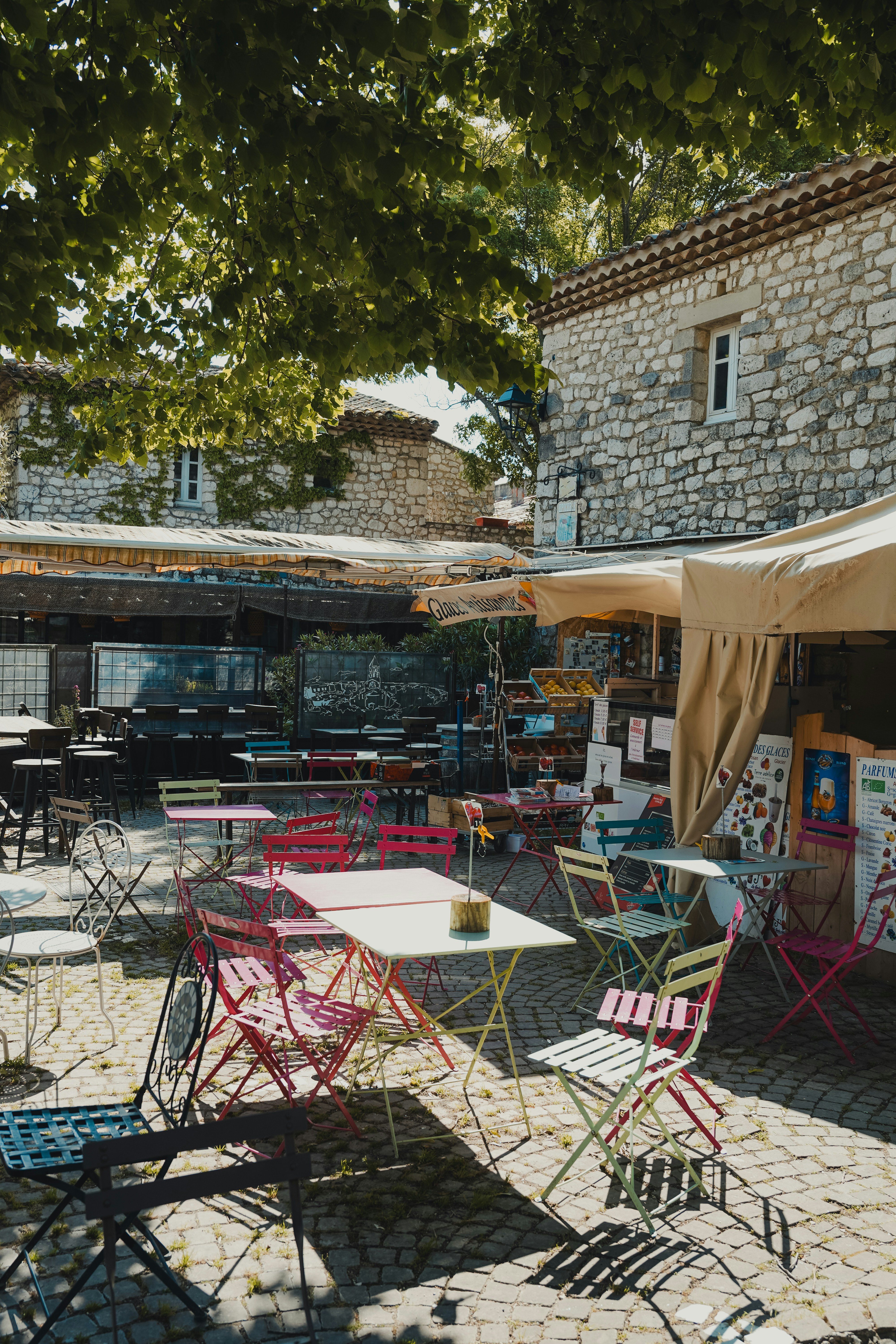 Bunte Stühle und Tische vor einem Steingebäude