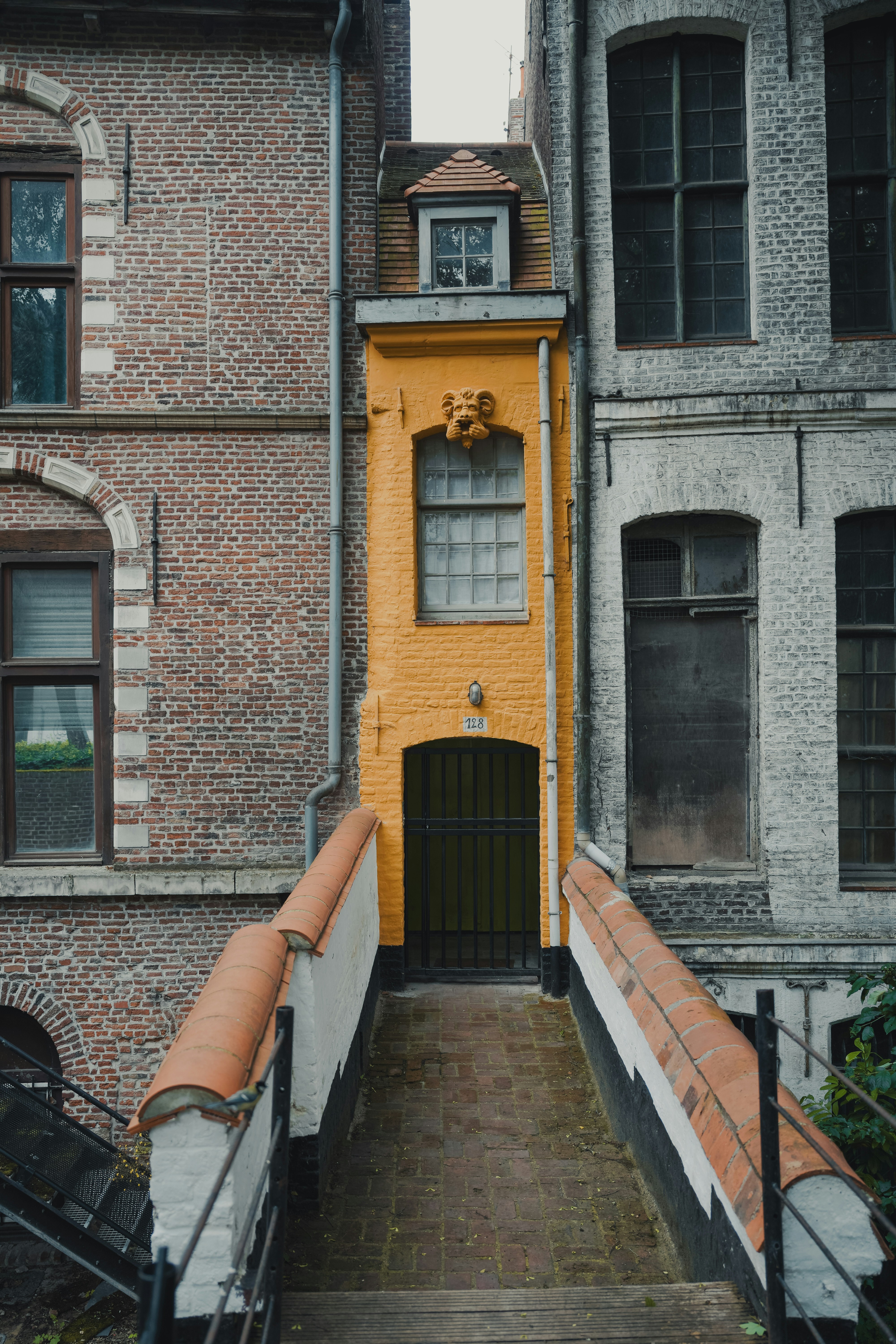 Schmales gelbes Gebäude zwischen Backstein- und grauen Gebäuden