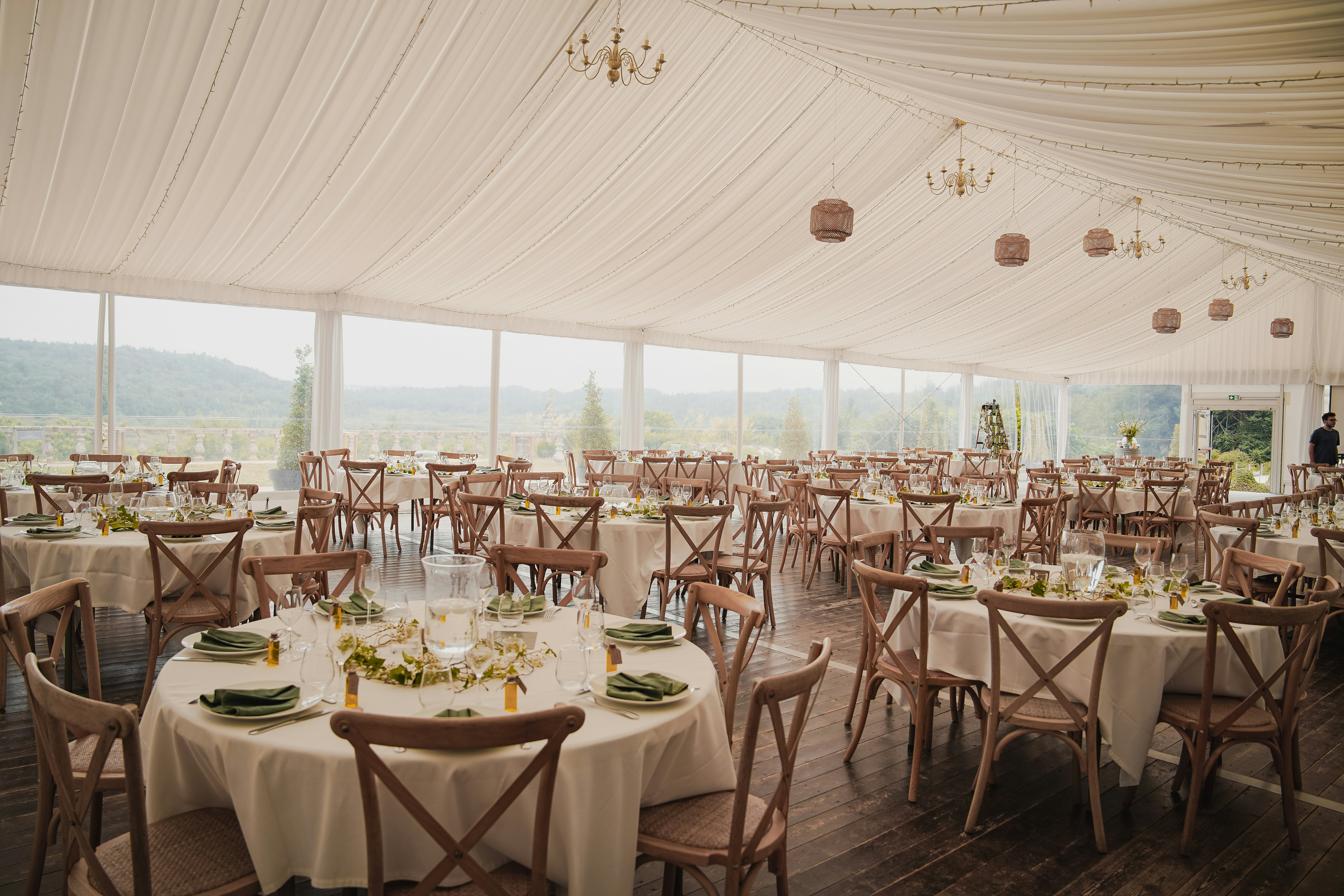 Elegant outdoor wedding reception under a tent with round tables