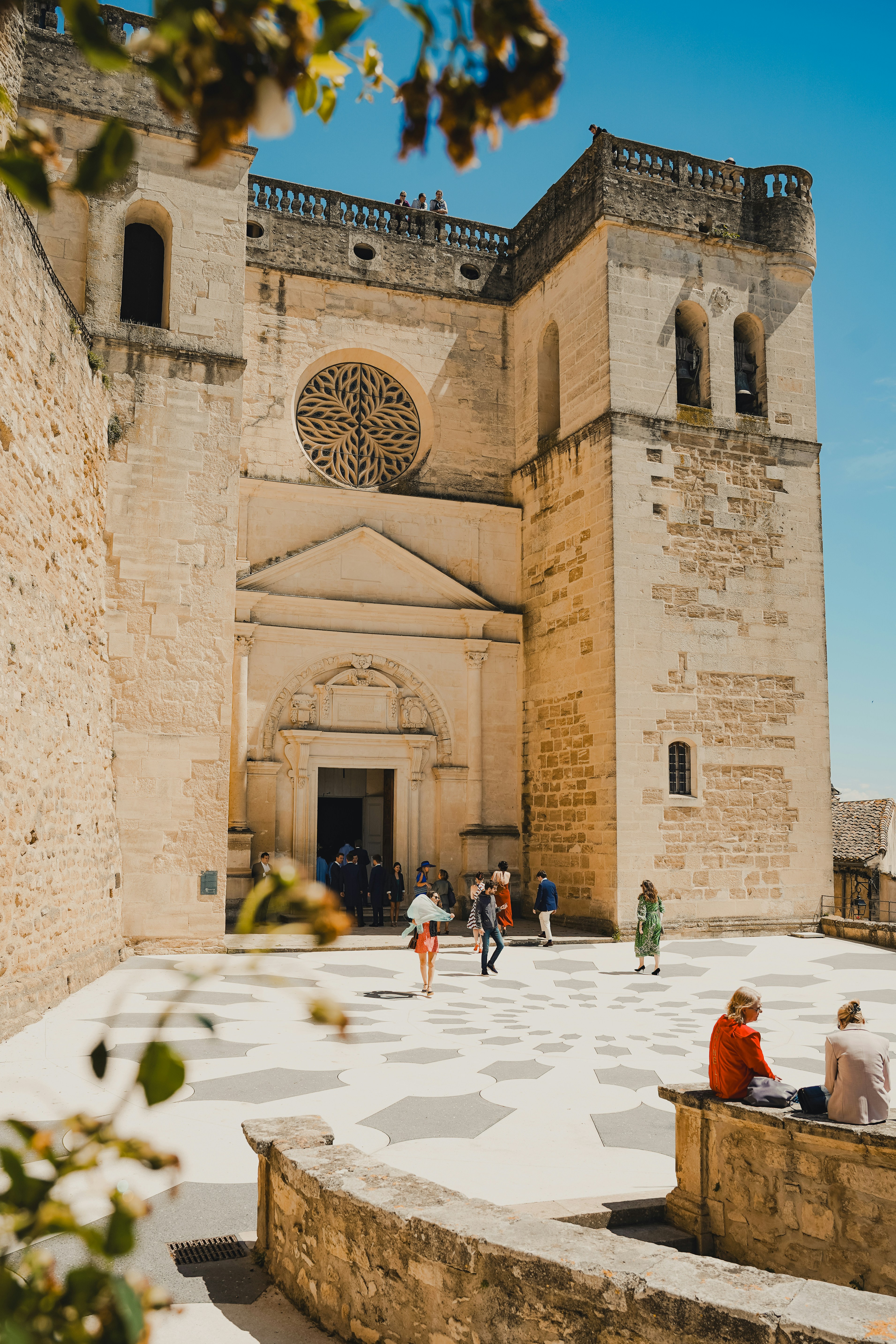 Menschen in einem Hof vor einer Steinkirche
