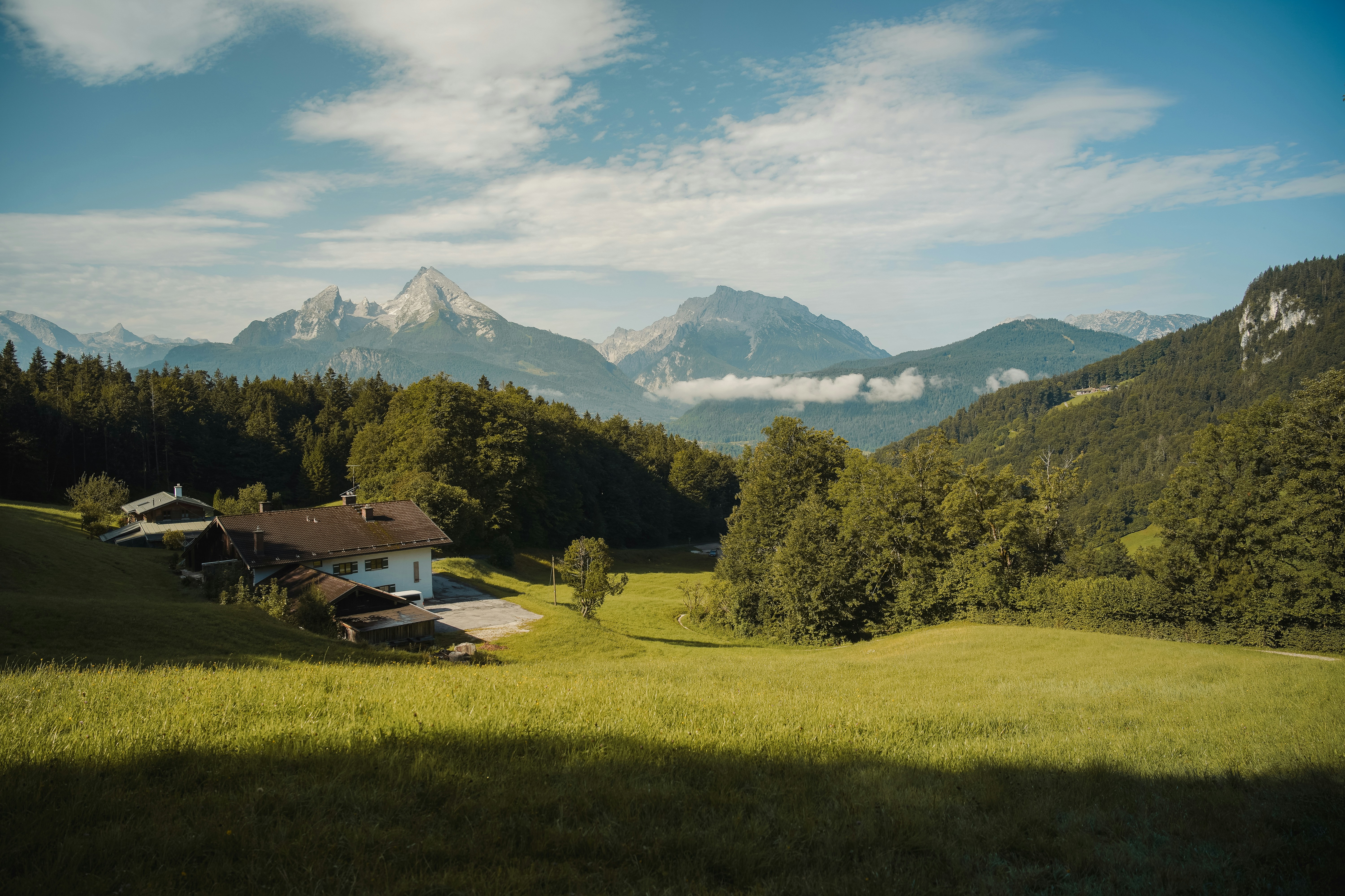 Ein Landhaus, eingebettet in ein grünes Tal mit Bergen.