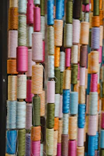 A colorful assortment of thread spools arranged vertically.
