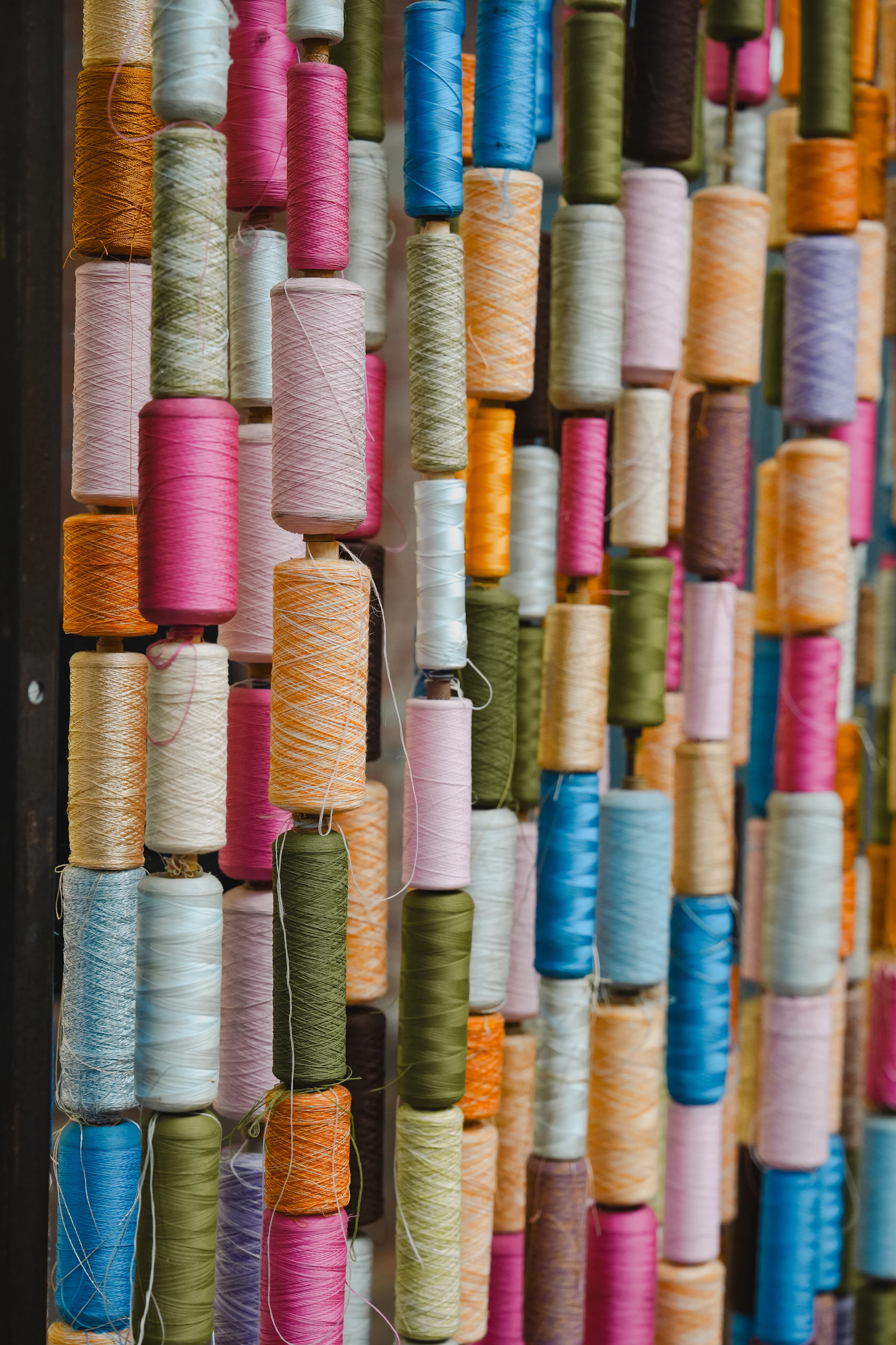 A colorful assortment of thread spools arranged vertically.