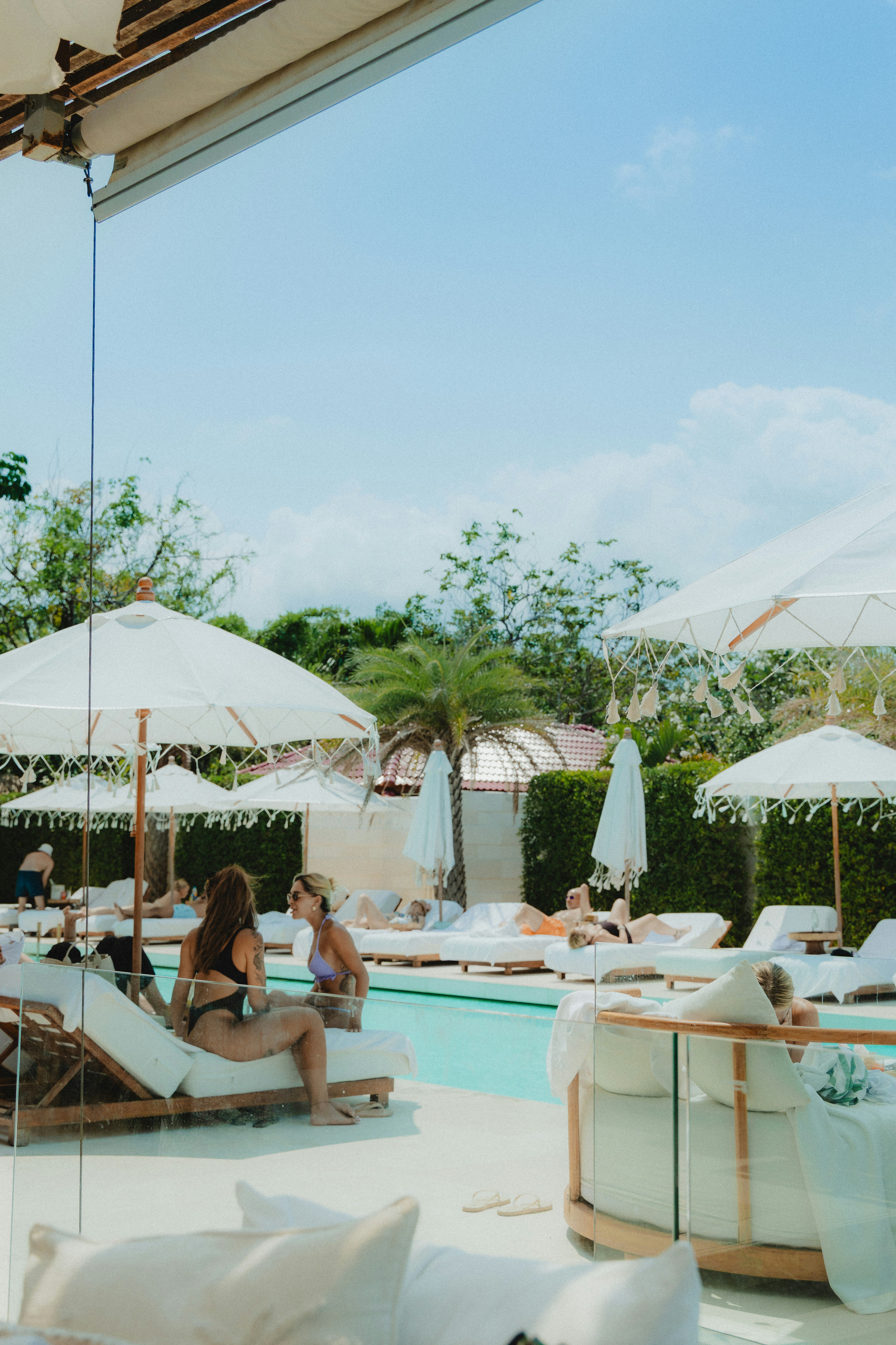 People relaxing by a resort swimming pool on lounge chairs.
