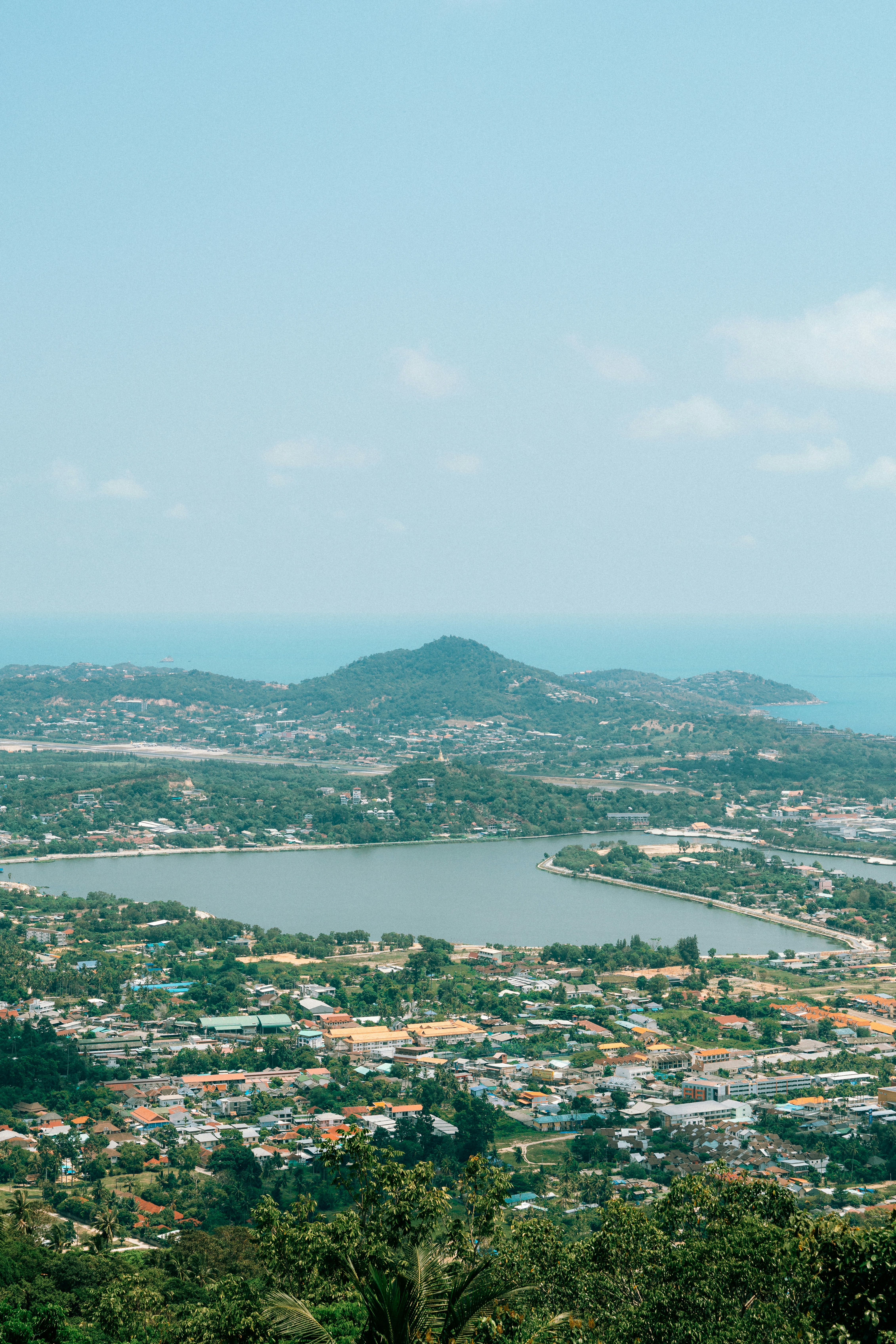 Lush green landscape with a lake and distant ocean.