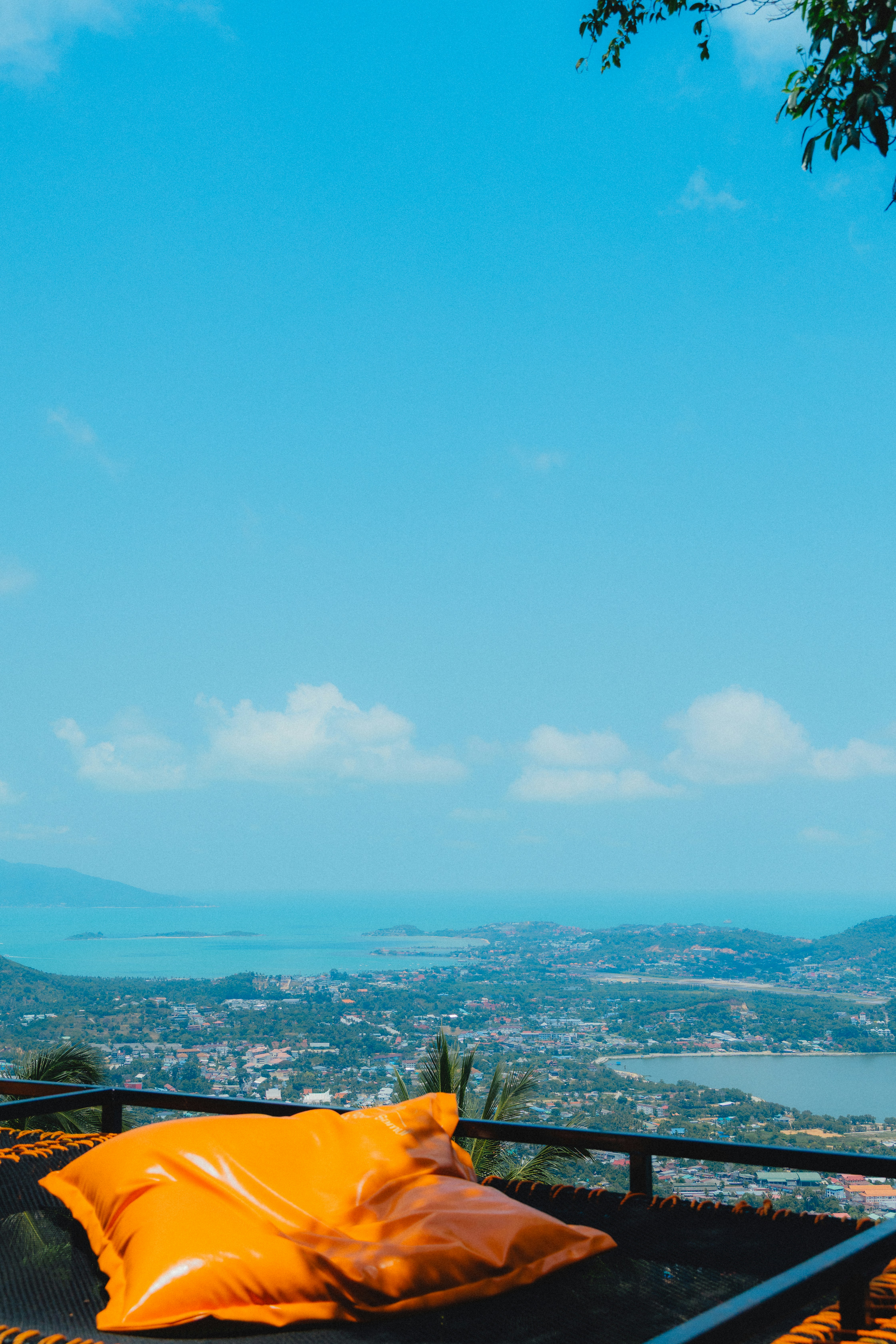Orange beanbag overlooks a coastal town and blue ocean.