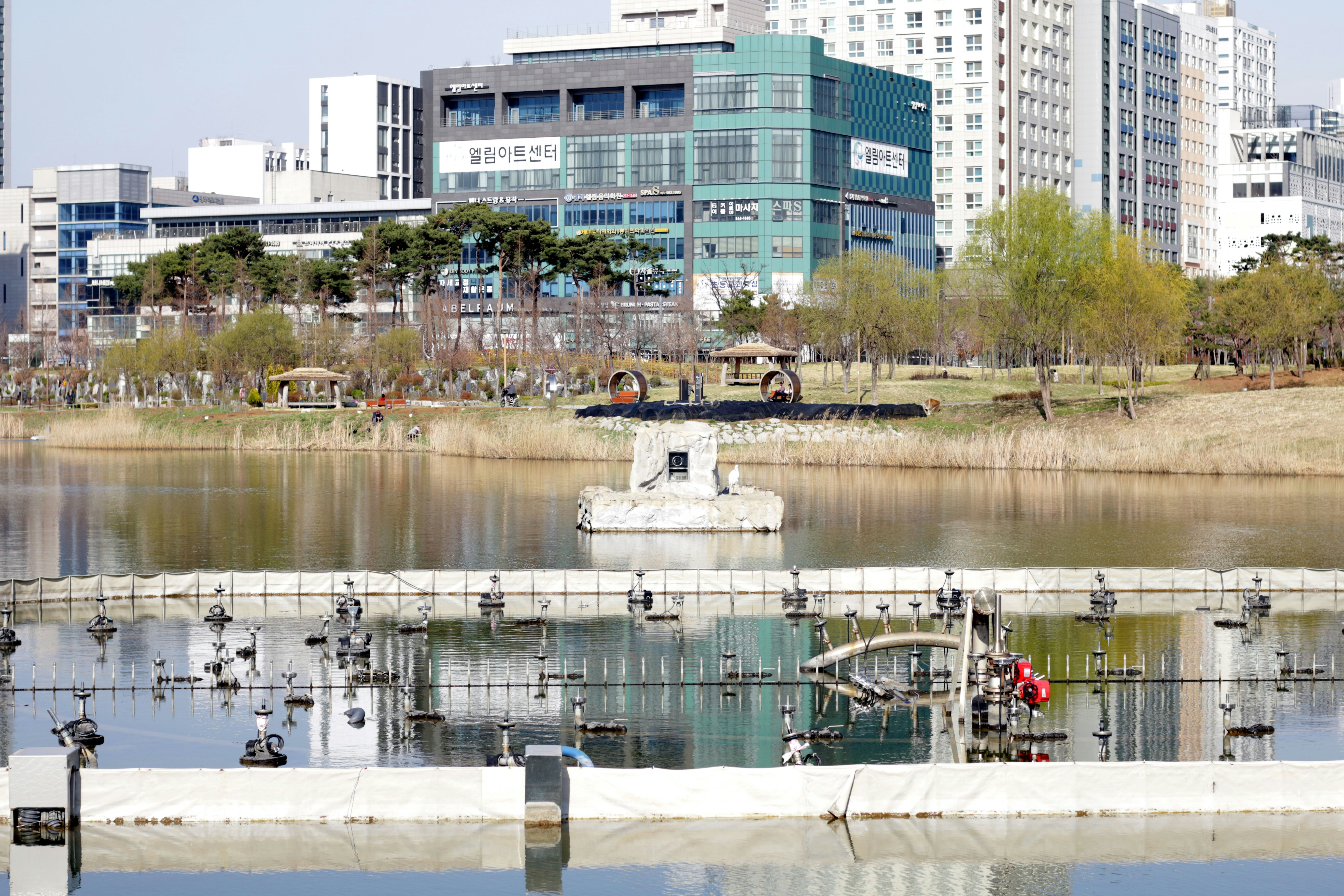 City buildings reflected in a calm river with a bridge.