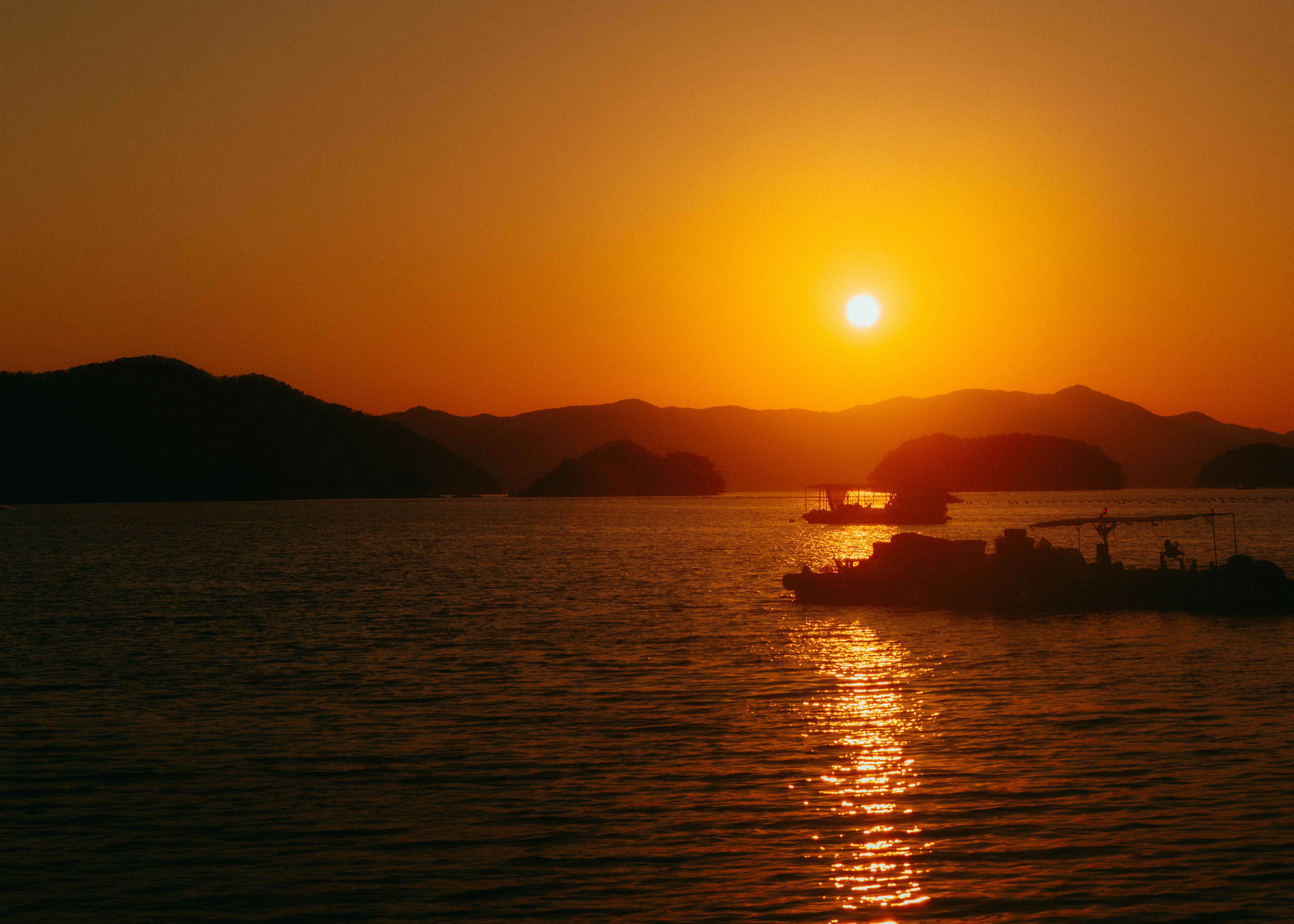 Sunset over a calm ocean with distant islands.