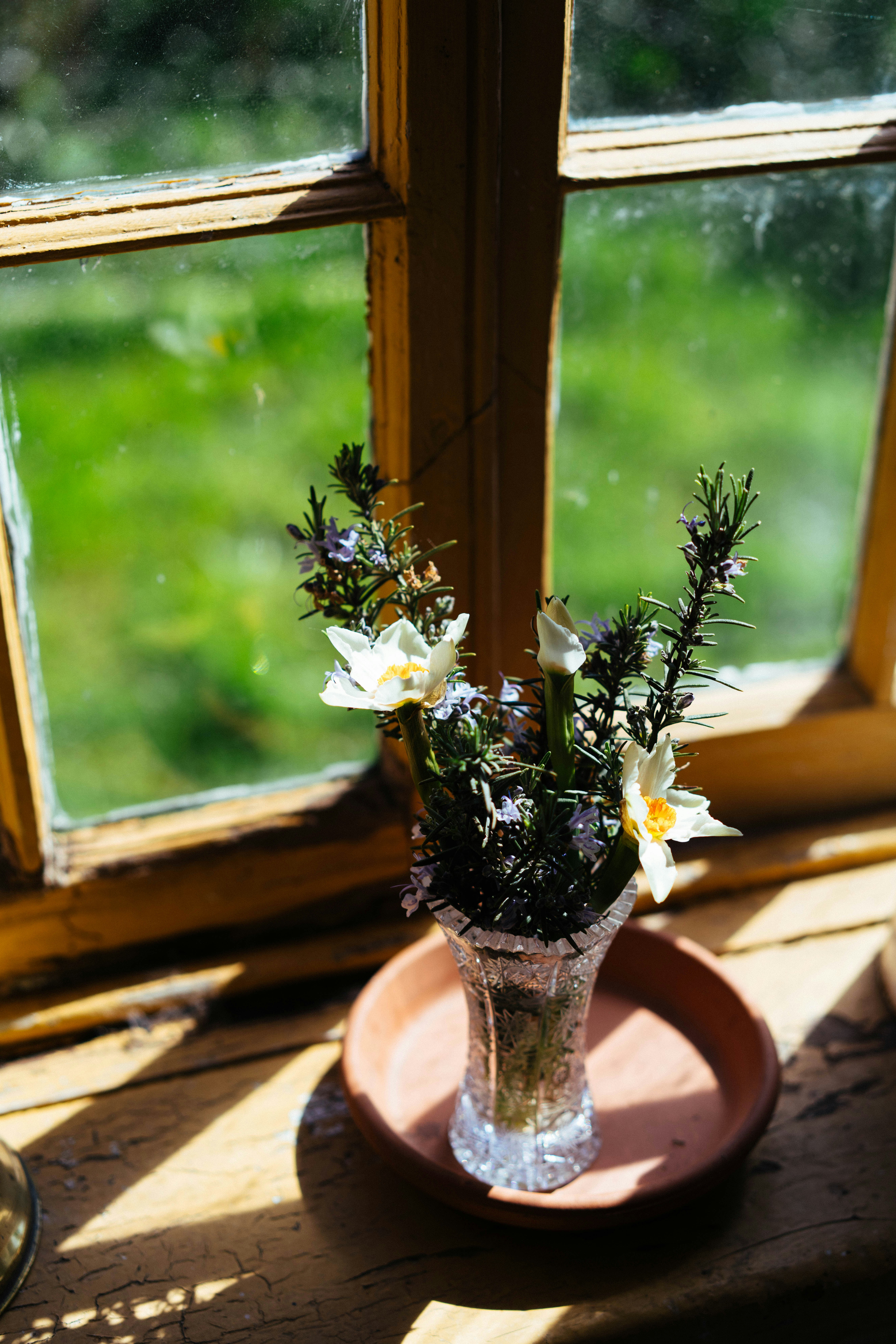 Un vase de fleurs repose sur un rebord de fenêtre.