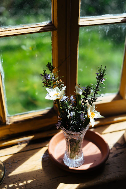 A vase of flowers sits on a windowsill
