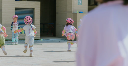 Children in helmets run across a paved area.