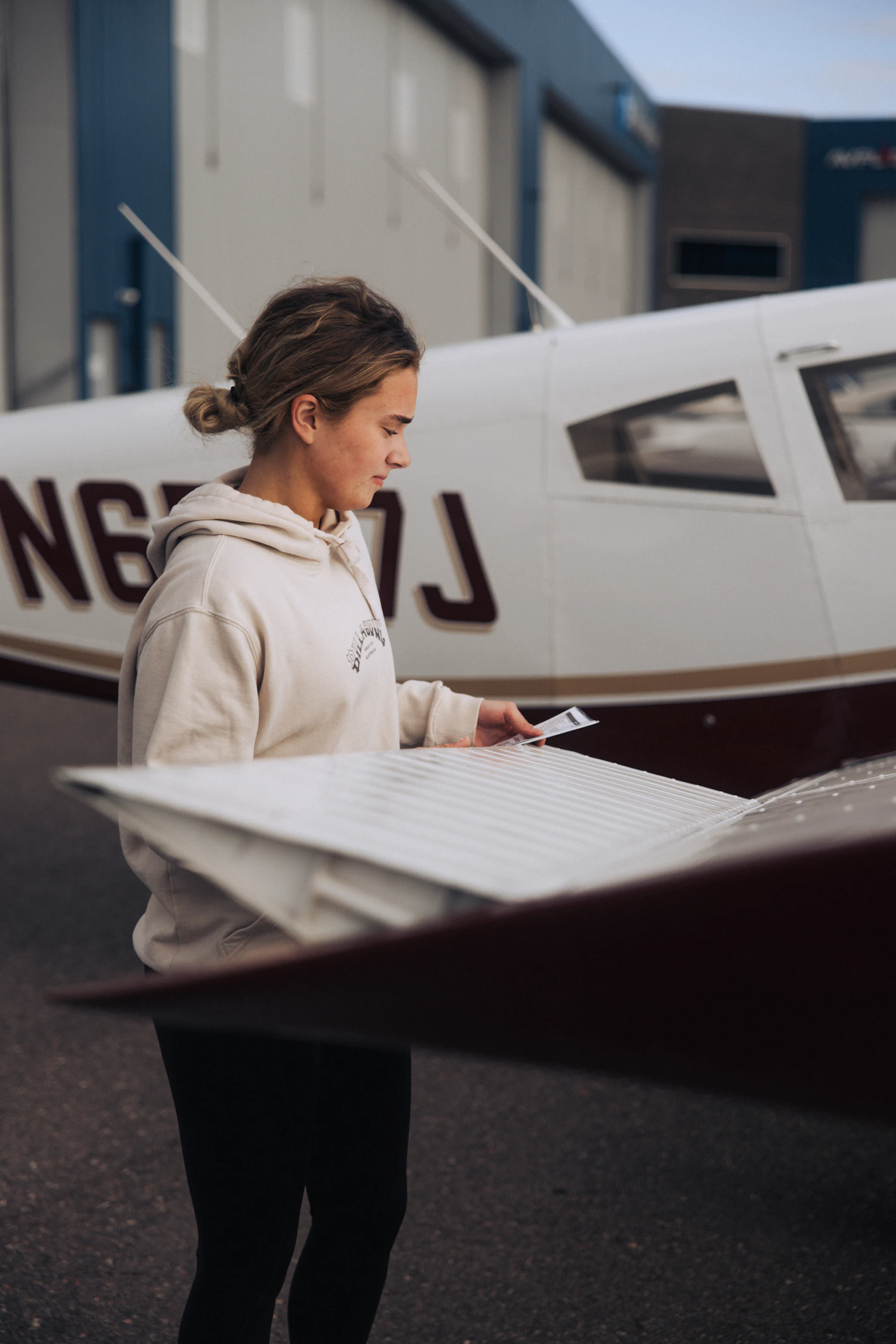 Angehende Pilotin bereitet sich neben einem Kleinflugzeug auf ihren Flug vor