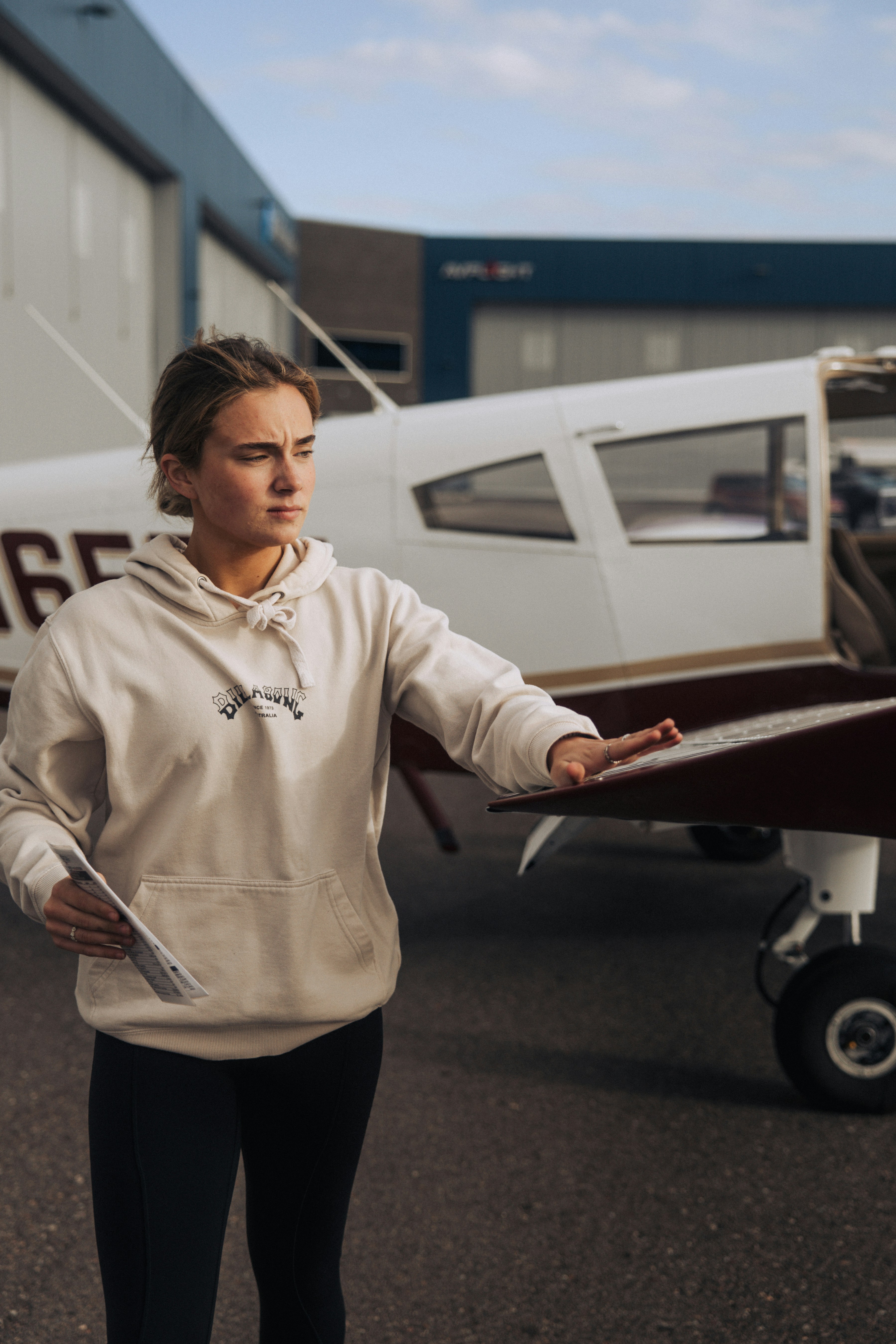 Junge Frau im Hoodie in der Nähe eines Flugzeugs