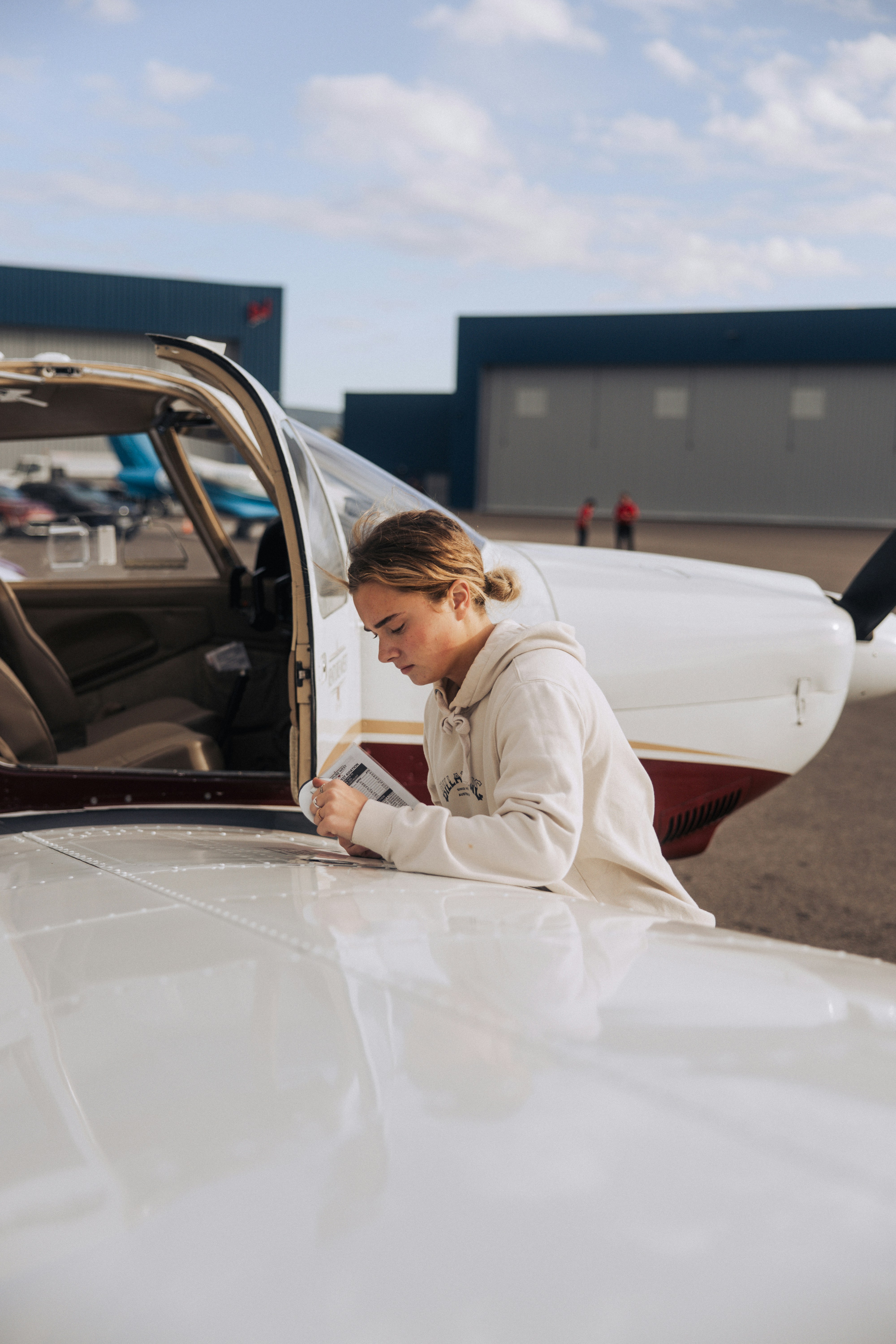 Young woman checking checklist by small airplane