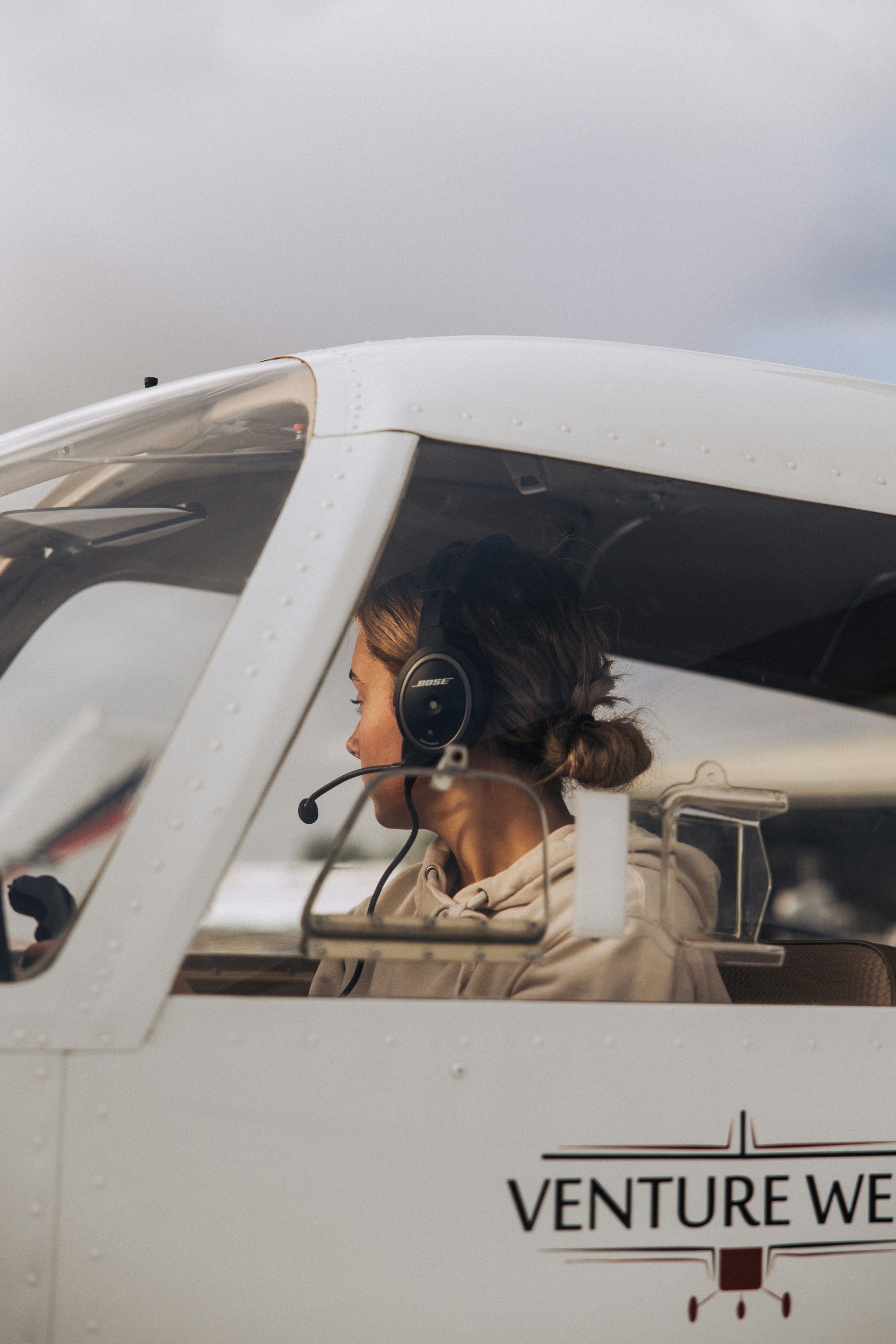 Junge Frau mit Headset sitzt im Flugzeugcockpit.