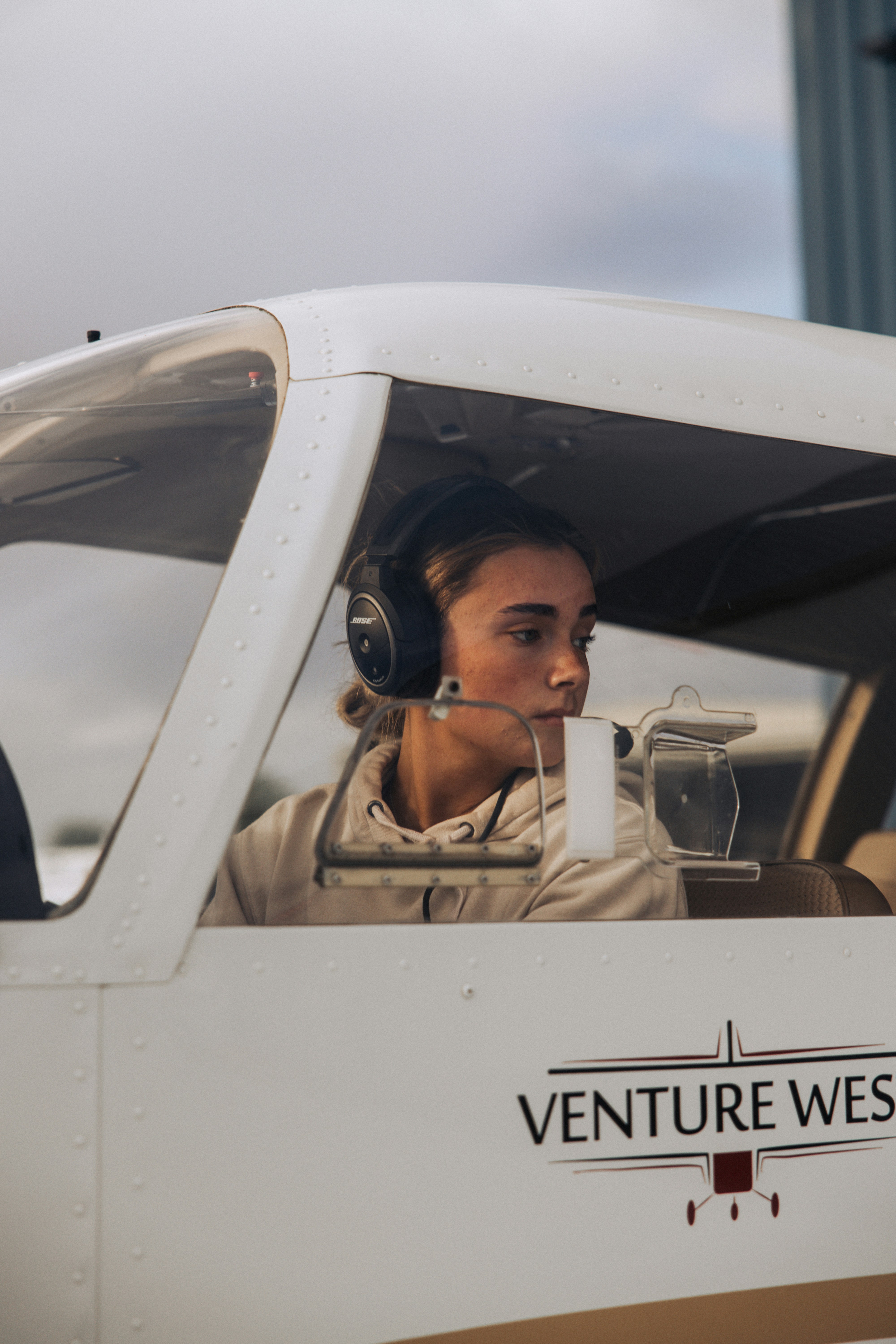 Young woman wearing headphones in airplane cockpit.
